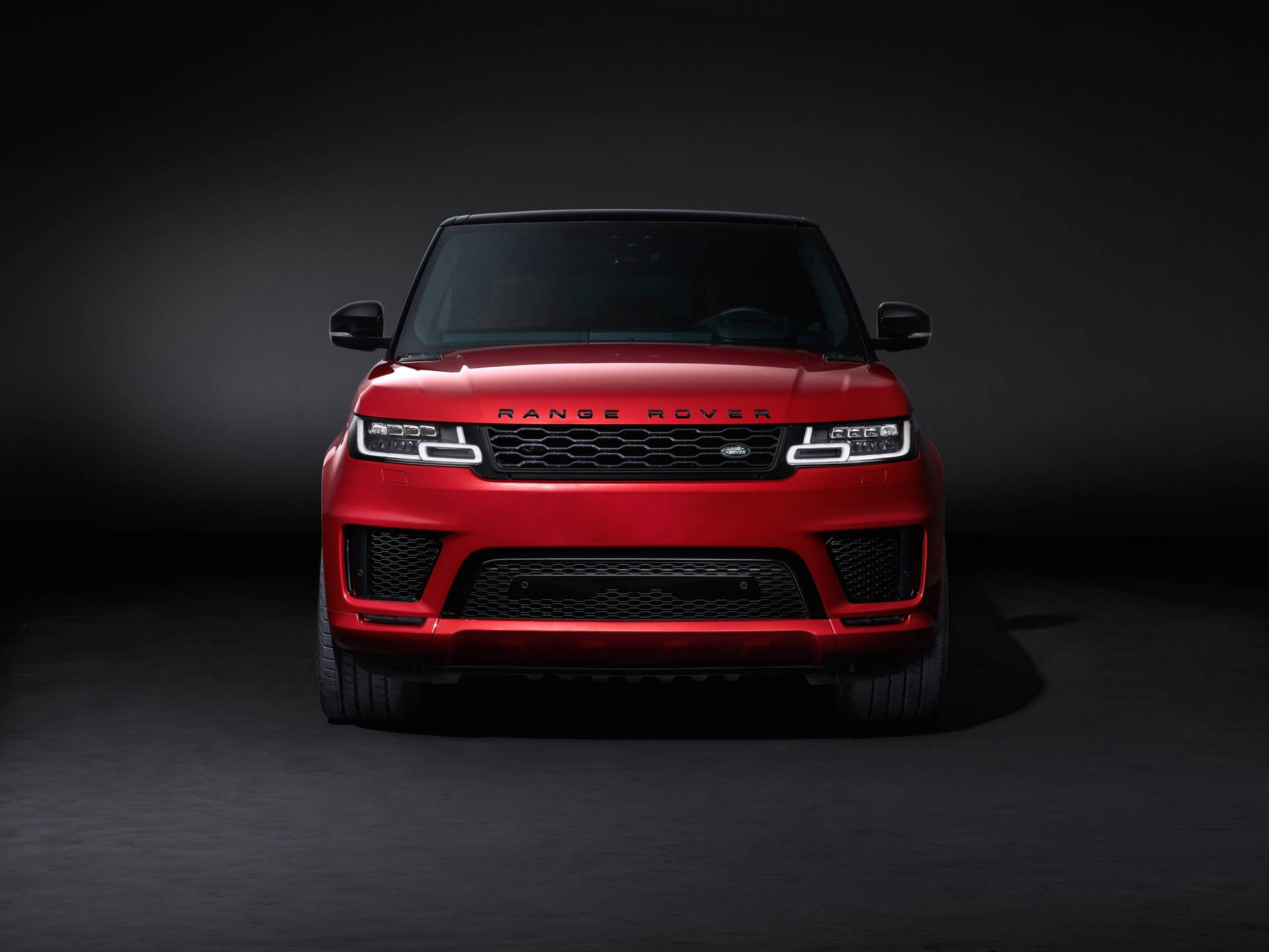 紅色 Range Rover SUV 在攝影棚中，帶有戲劇性燈光。