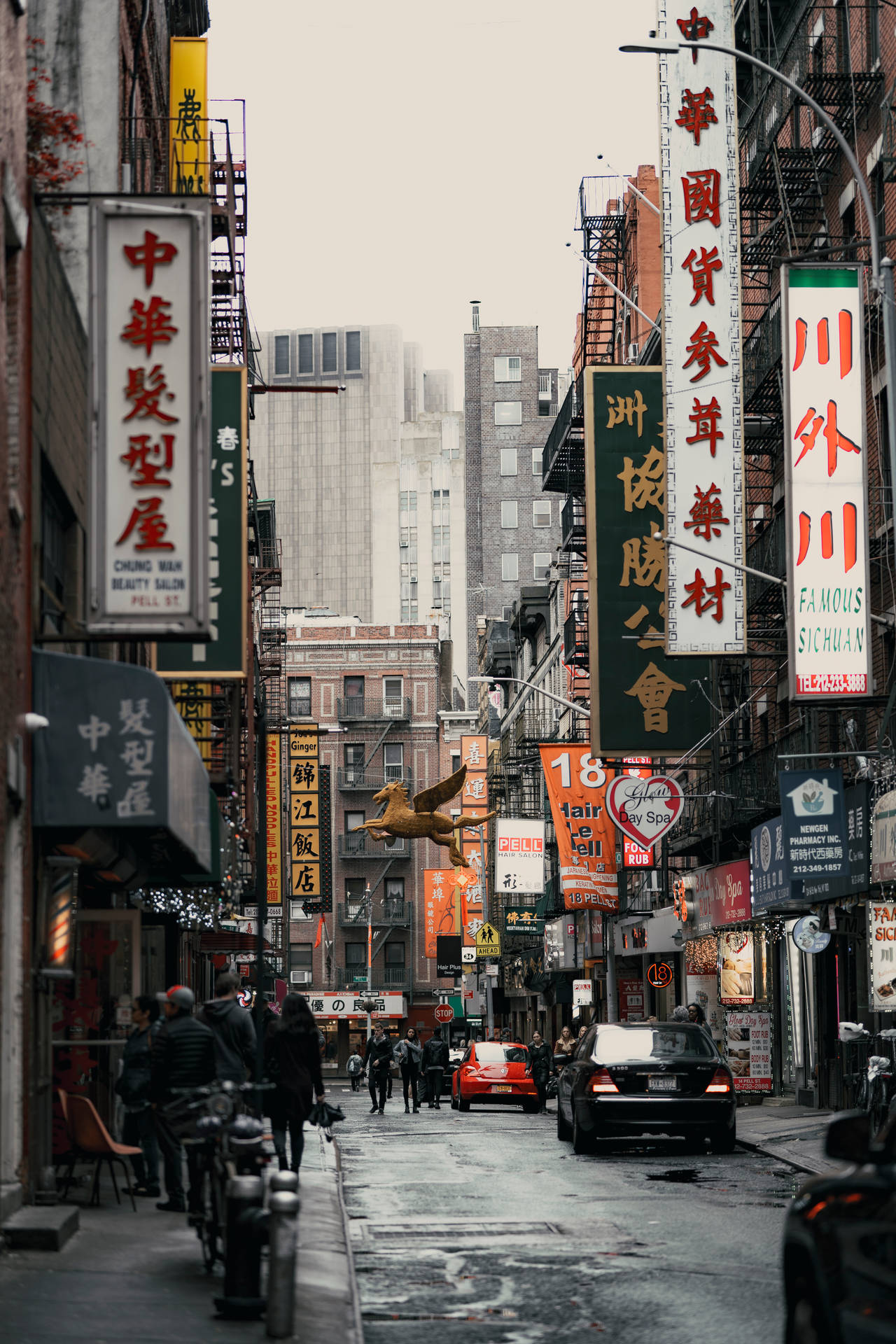 繁忙的唐人街街道，有中文招牌和行人走在灰濛濛的天空下。