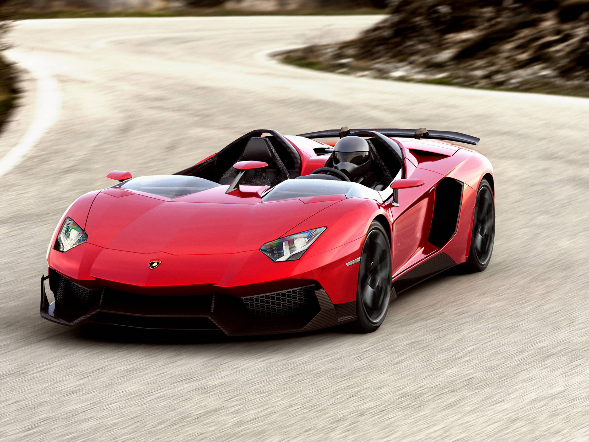紅色林寶堅尼 Aventador Roadster 在日落時分於蜿蜒道路上奔馳。