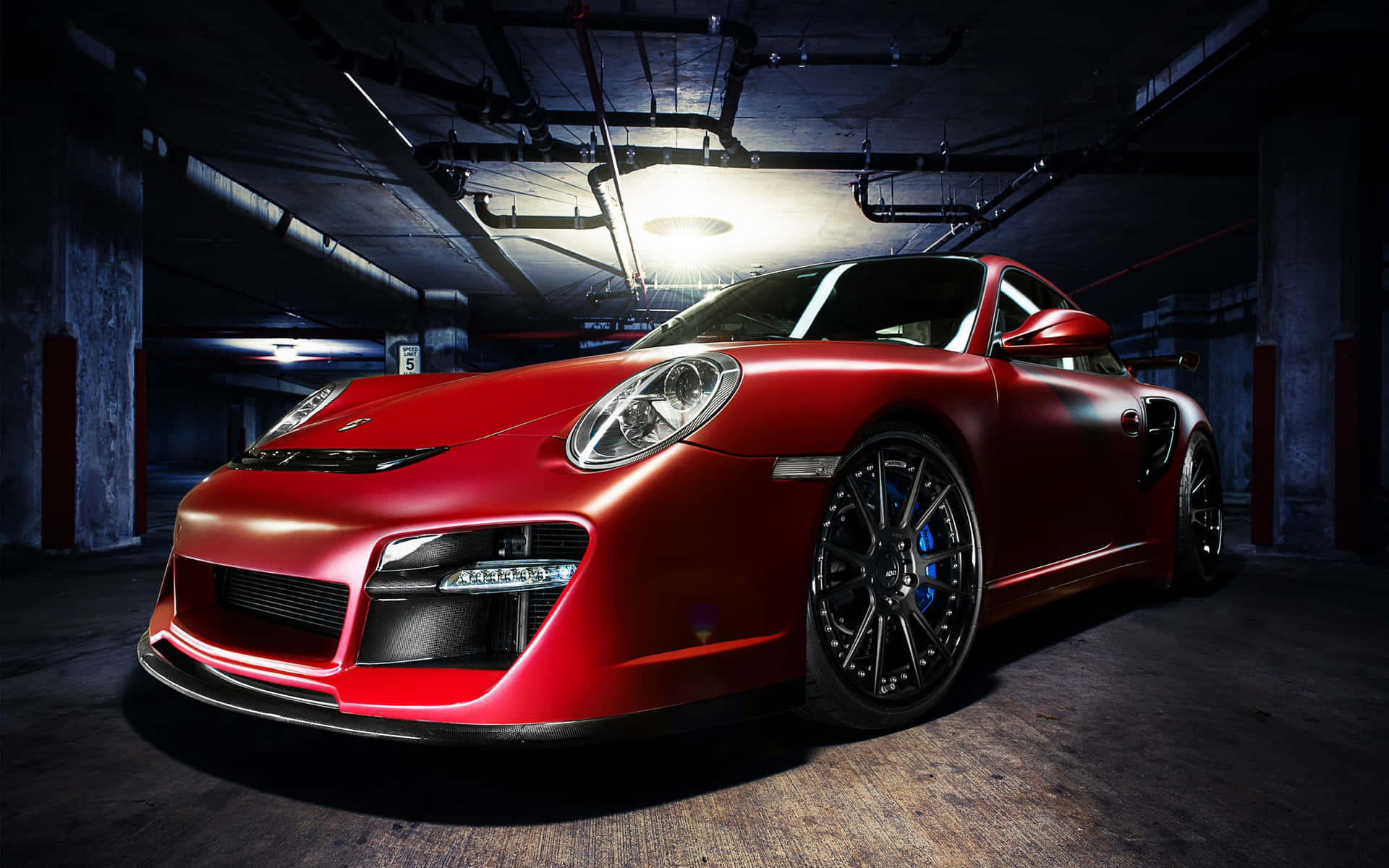 光亮的紅色保時捷911 Turbo停放在昏暗的地下車庫中。