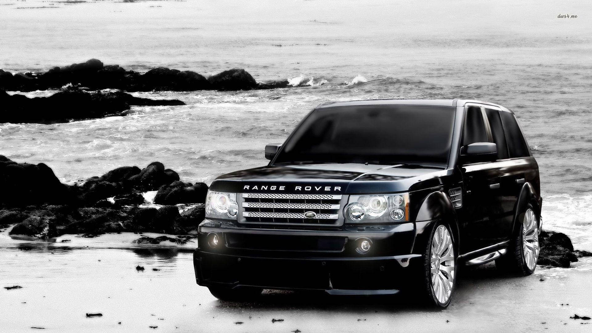 黑色Range Rover SUV停泊在岩石海灘上，海浪拍打。