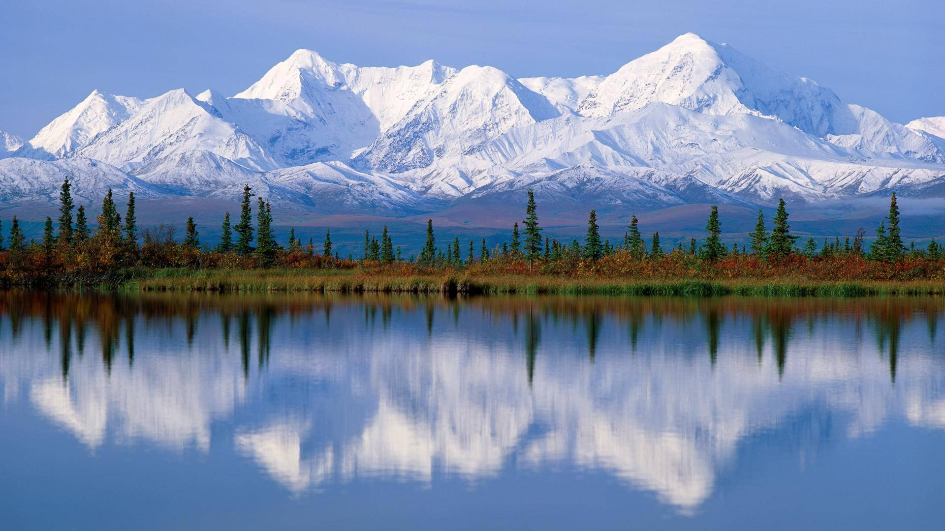 4K 雪山與湖景 壁紙 — 積雪覆蓋的山峰在平靜的湖泊後方雄偉地聳立，湖面倒映著山頂和秋天的樹木。