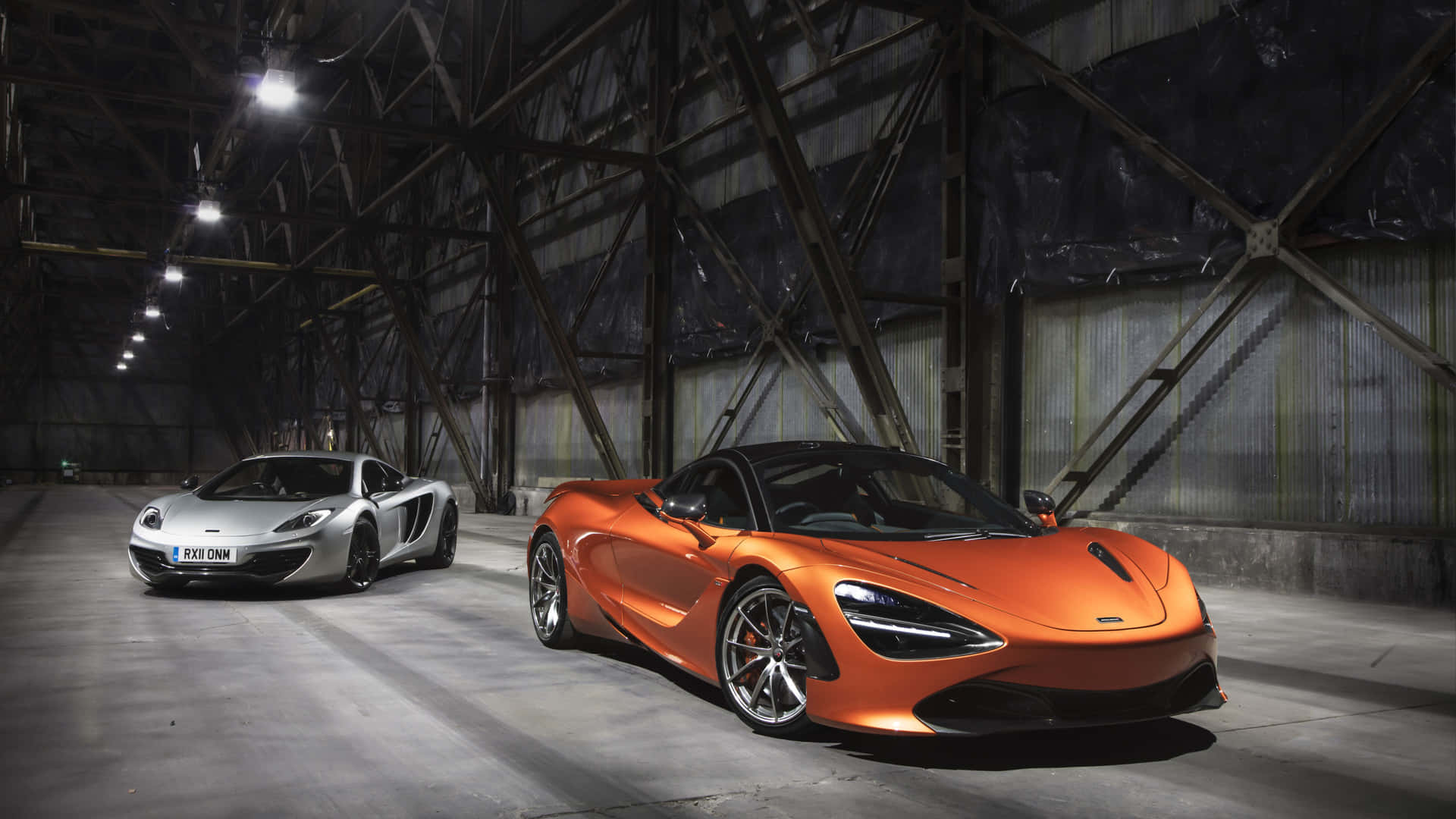 兩輛McLaren超級跑車停放在昏暗的工業倉庫中。