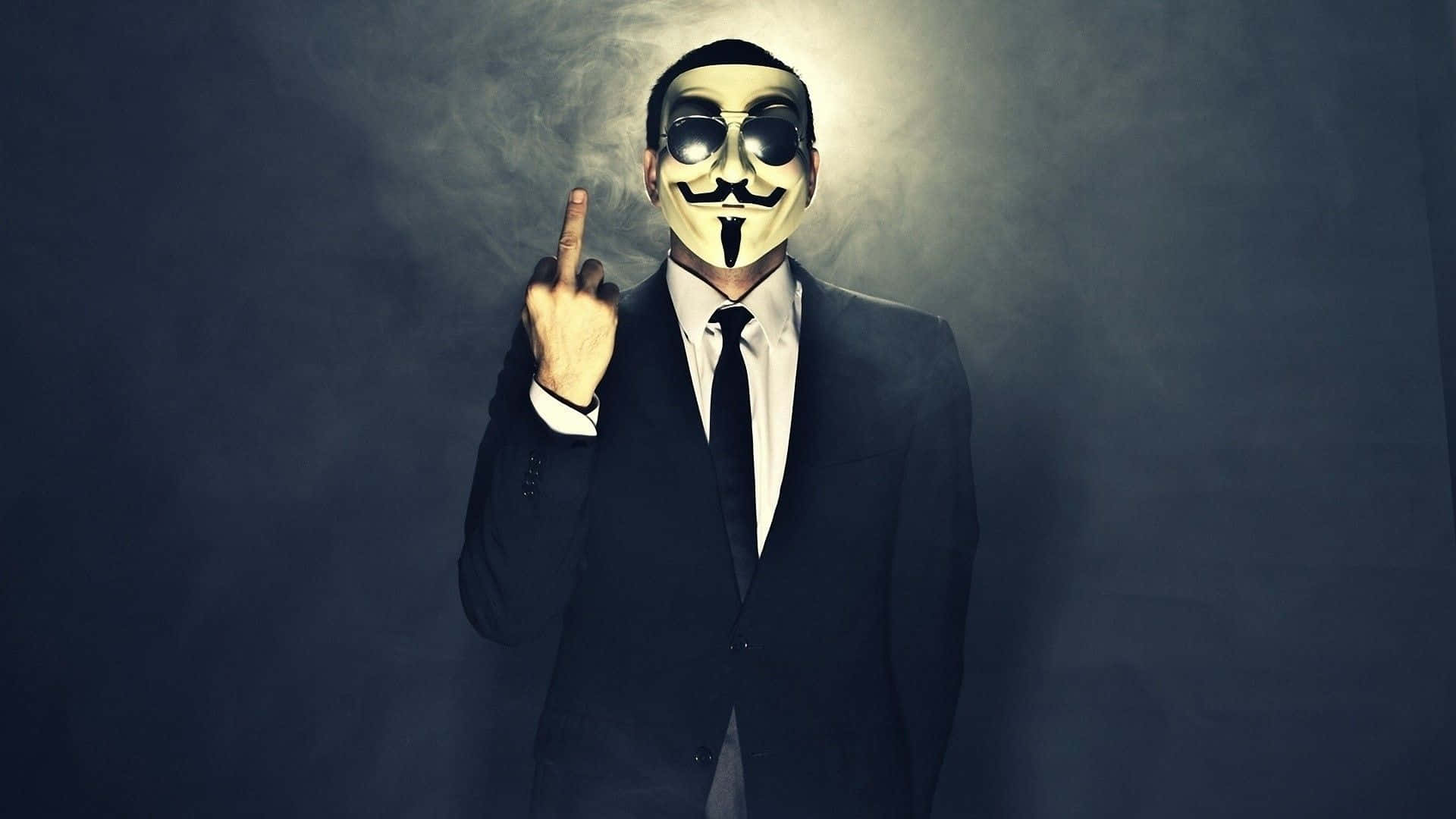 身穿西裝和蓋伊·福克斯面具的人在煙霧瀰漫的黑暗環境中做出豎中指手勢。