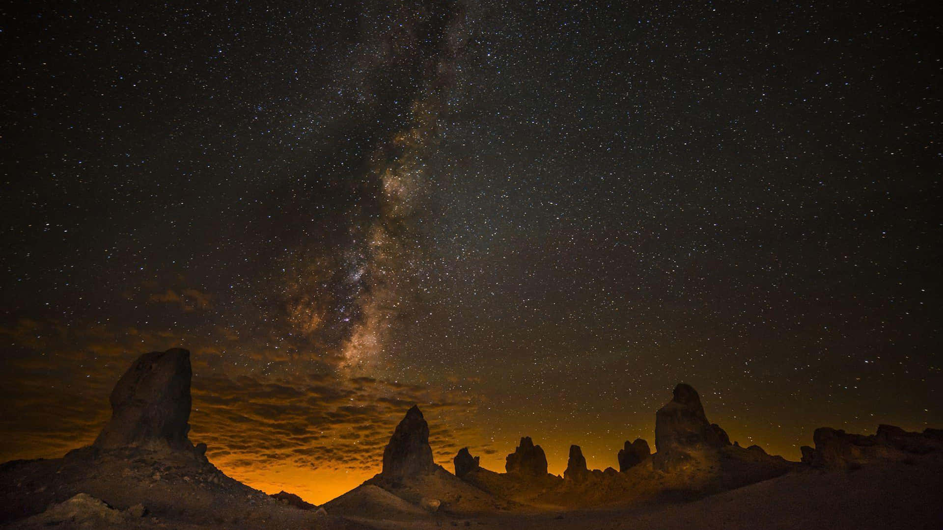 夜晚沙漠岩石層上的銀河系