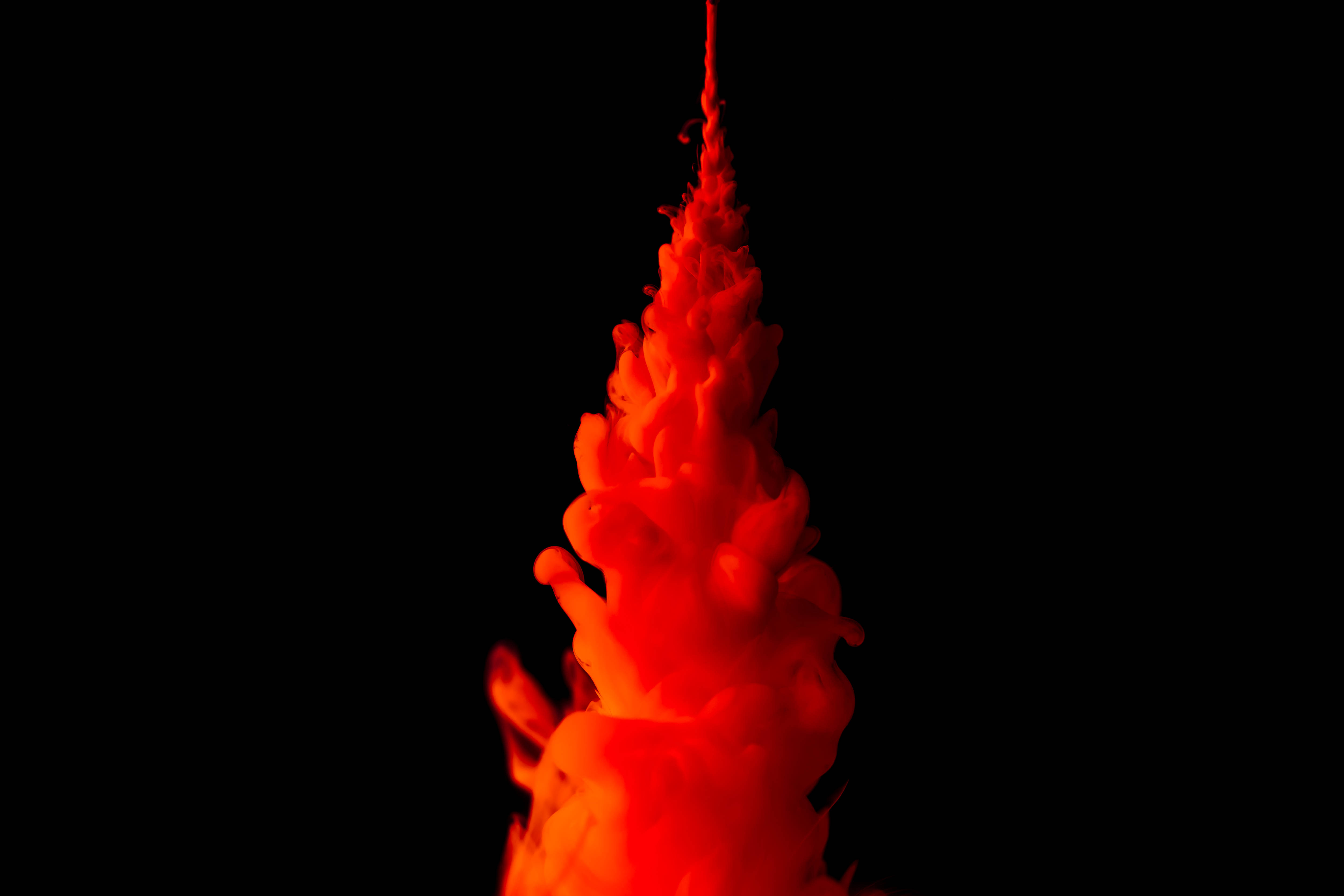 4K橙色墨水噴射 壁紙 — 鮮豔的紅色墨水在純黑色背景上以慢動作向上噴湧，形成抽象的火焰瀑布。
