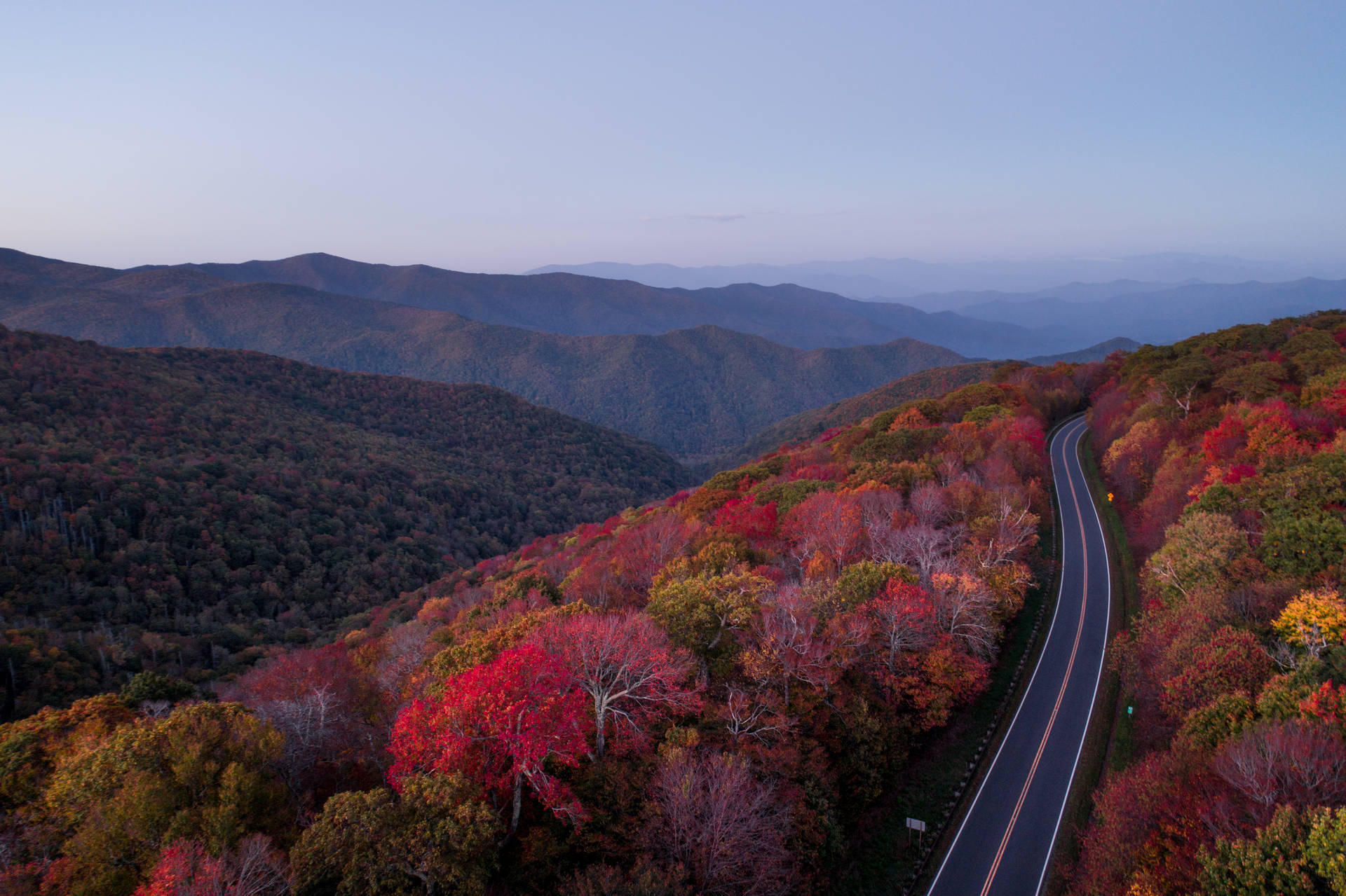 暮色中蜿蜒的道路穿過色彩繽紛的秋山
