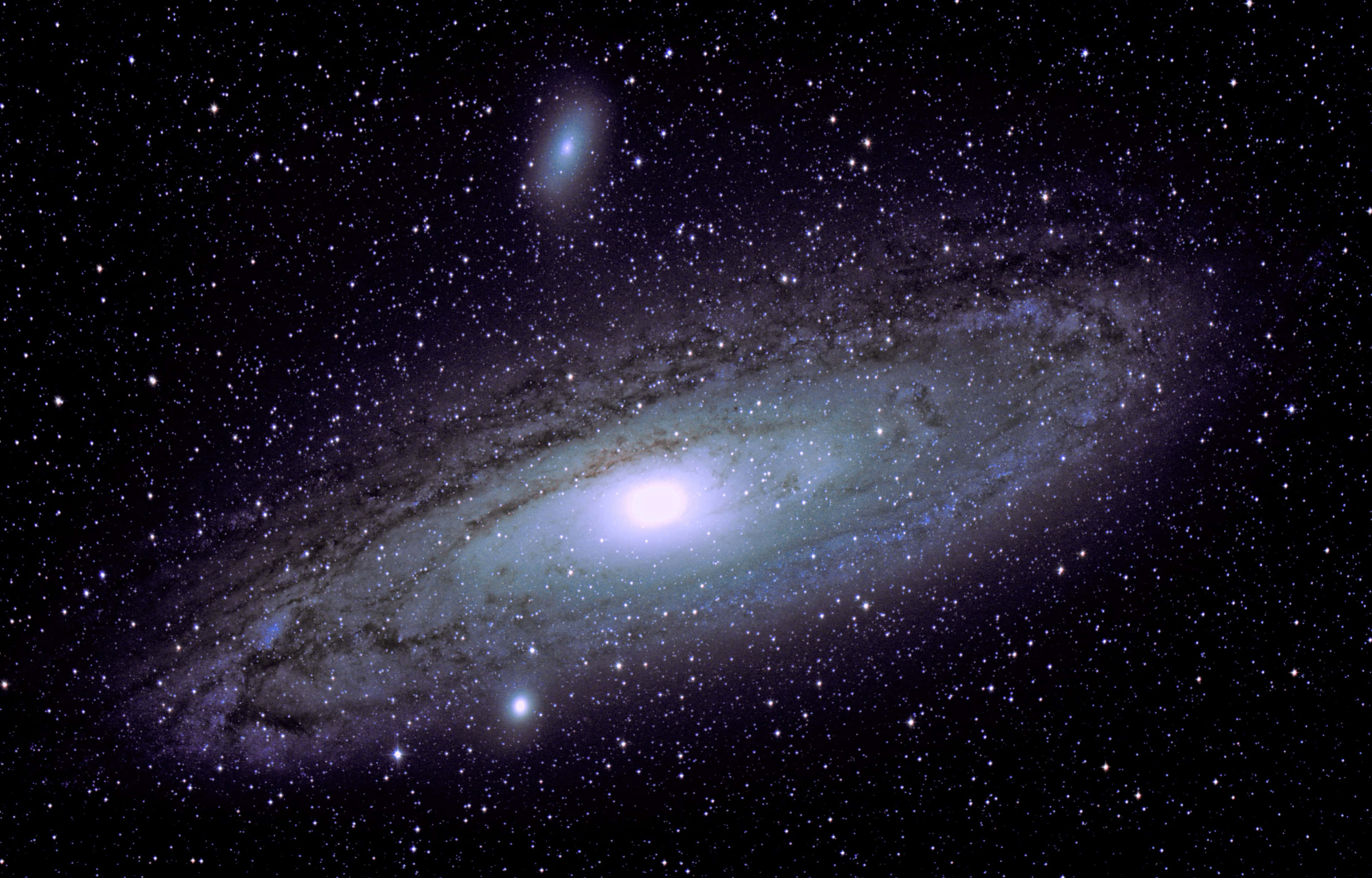 4K超高清仙女座星系壯觀視覺 壁紙 — 一個令人嘆為觀止的螺旋星系，在紫色和黑色的星場中發出藍色和白色的光芒。