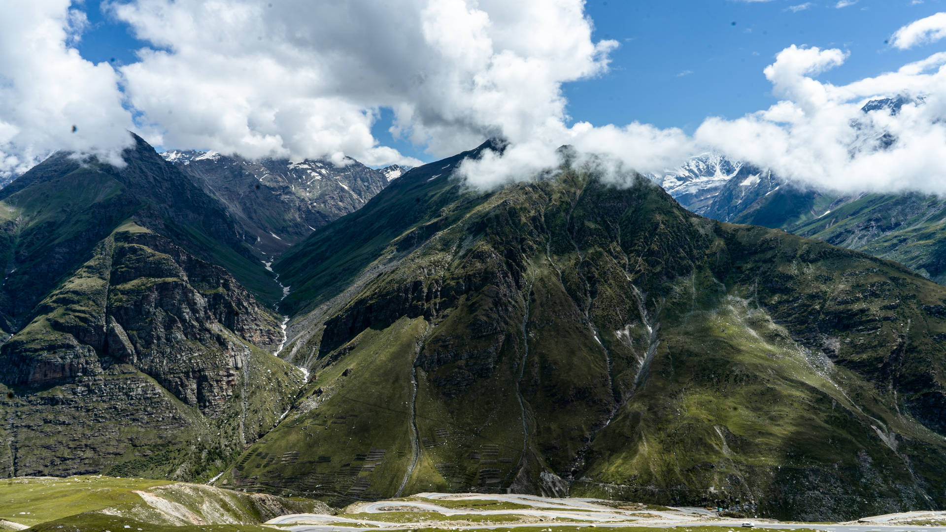 白雪覆蓋的山峰、翠綠山坡、藍天白雲。