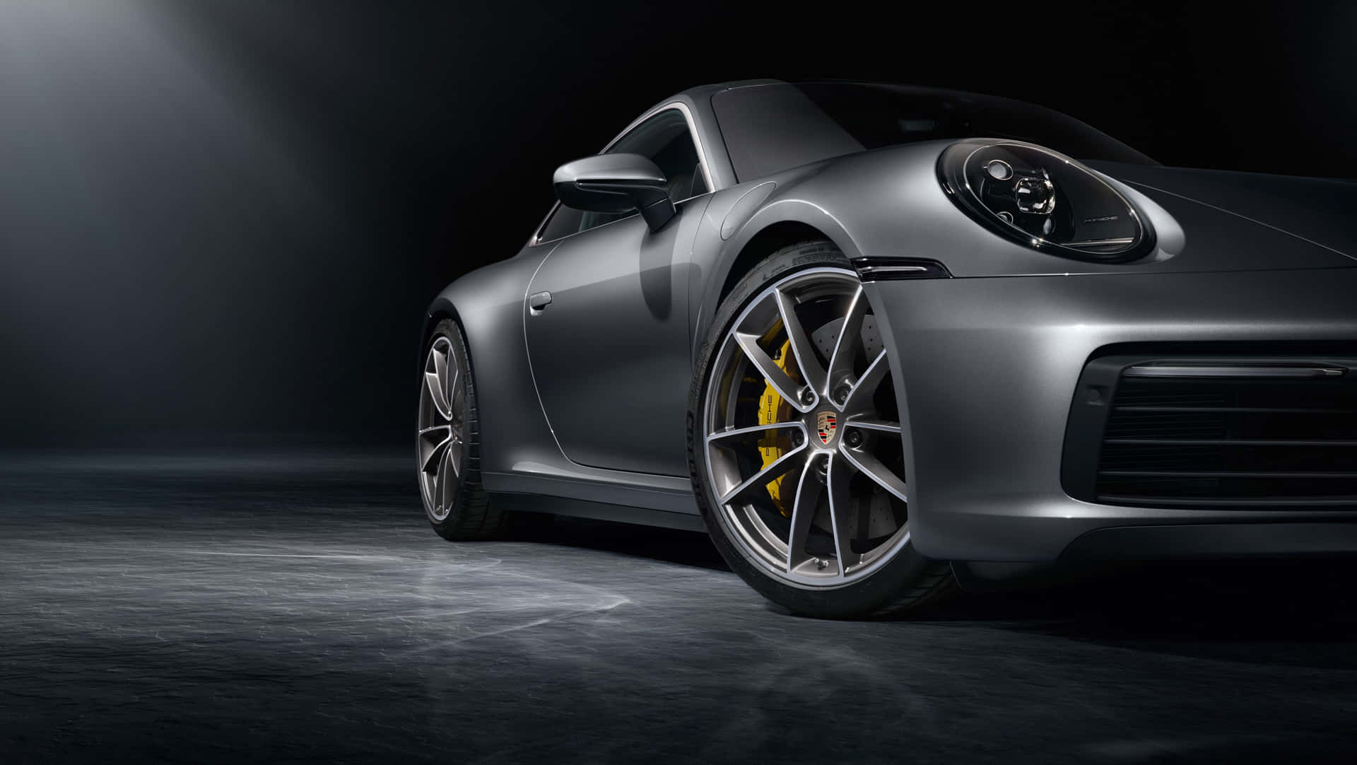銀色保時捷911跑車，帶黃色制動卡鉗，在黑暗的攝影棚燈光下。