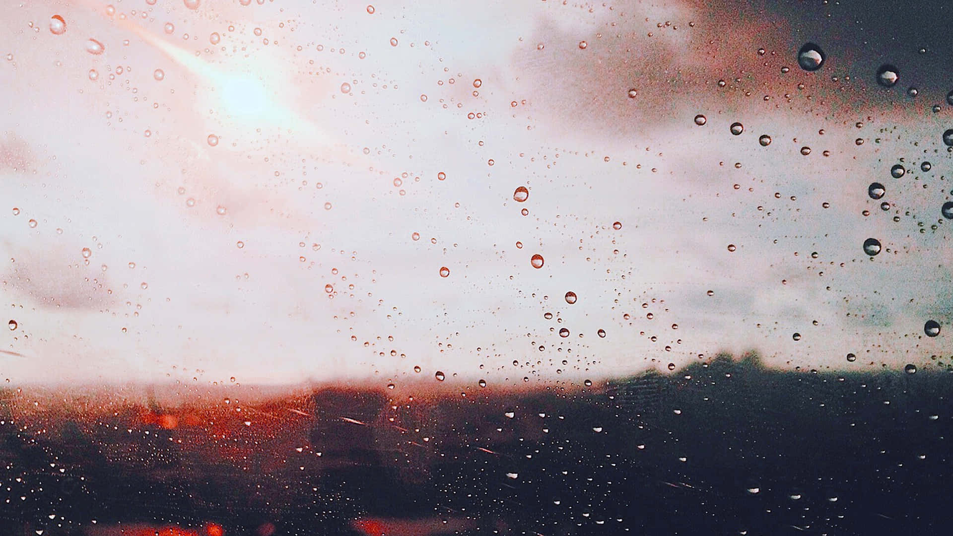 窗戶上的雨滴，俯瞰著夕陽下朦朧的城市。