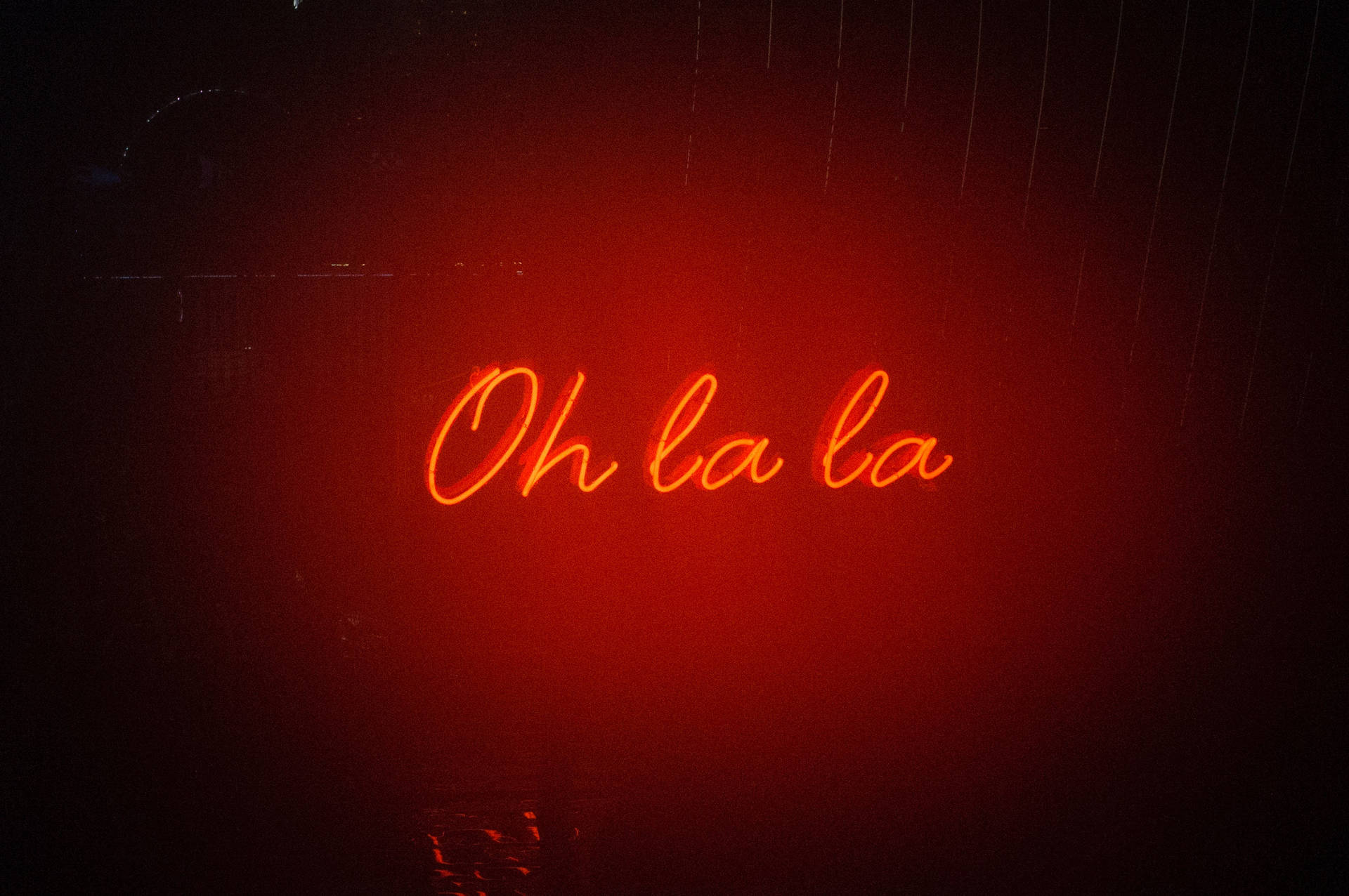 雨夜窗戶上寫著 Oh la la 的紅色霓虹燈牌。