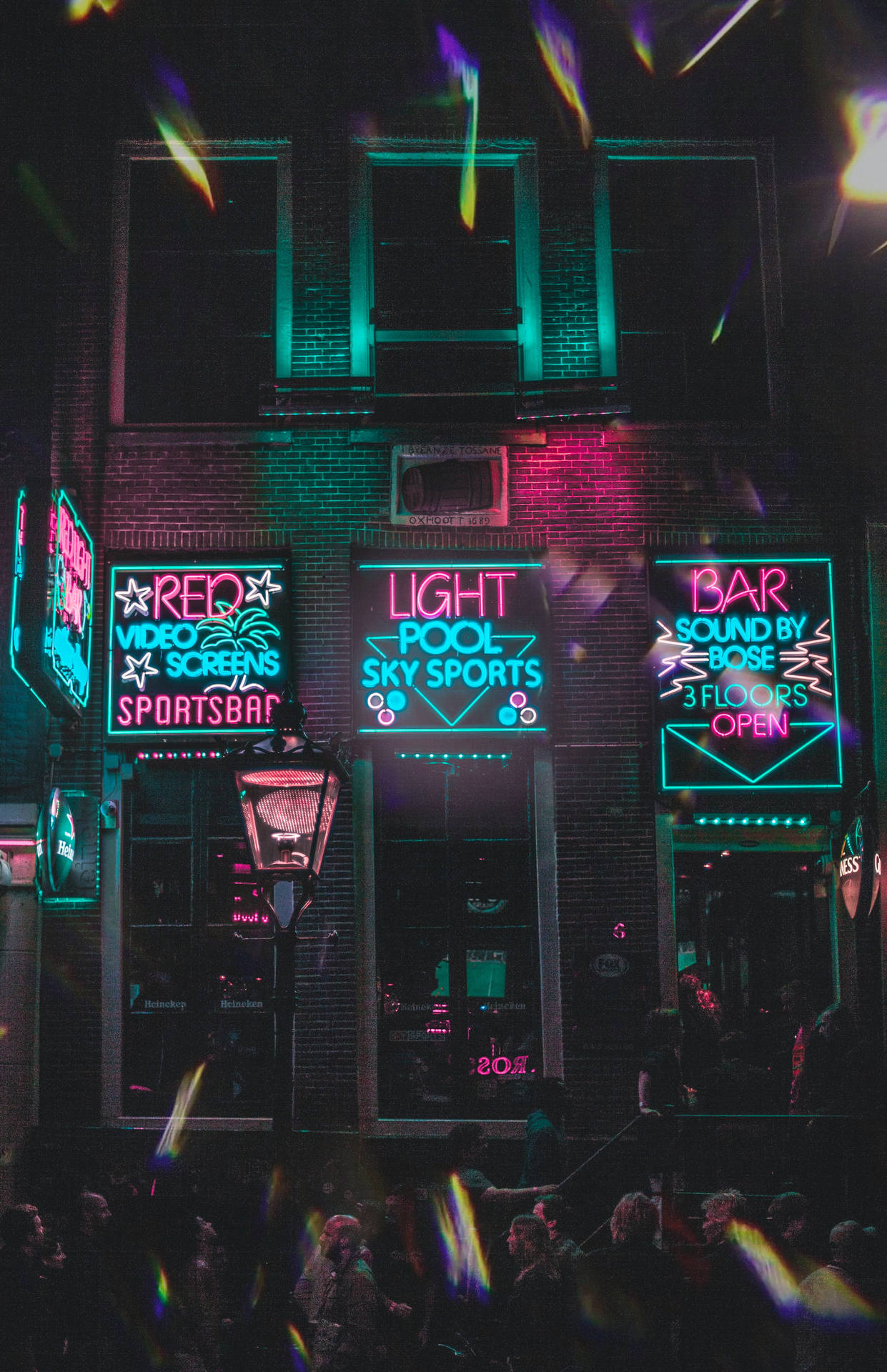 霓虹燈照亮的體育酒吧建築，夜間外面聚集人群。
