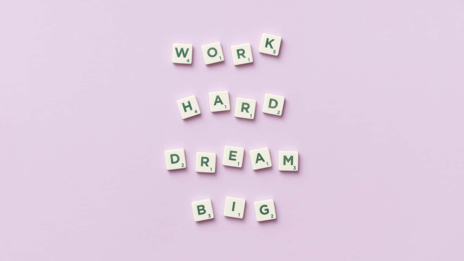 Scrabble 字母塊在薰衣草背景上拼出 work hard dream big