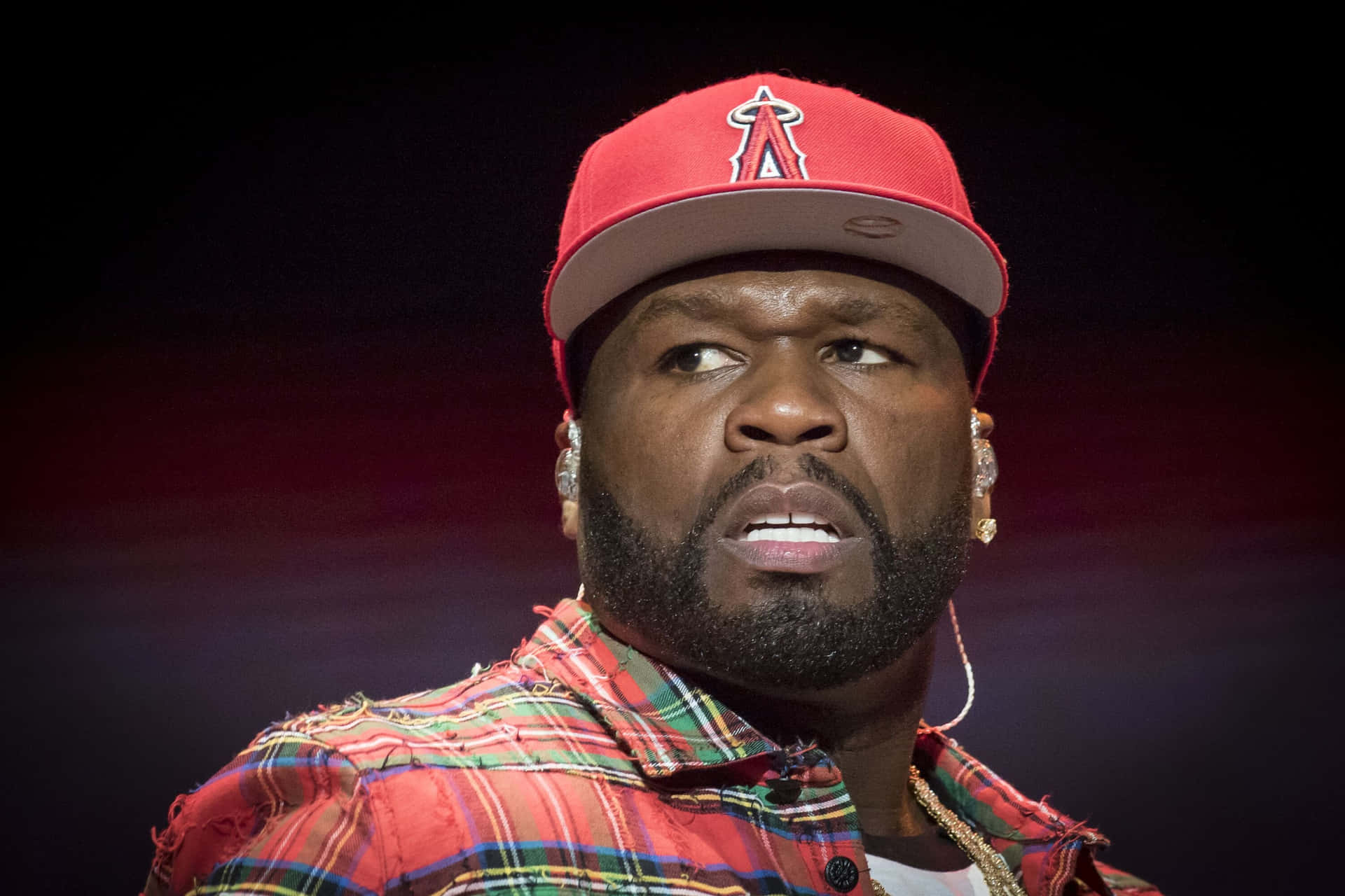 50 Cent 戴紅色帽和格仔恤衫在舞台上表演。
