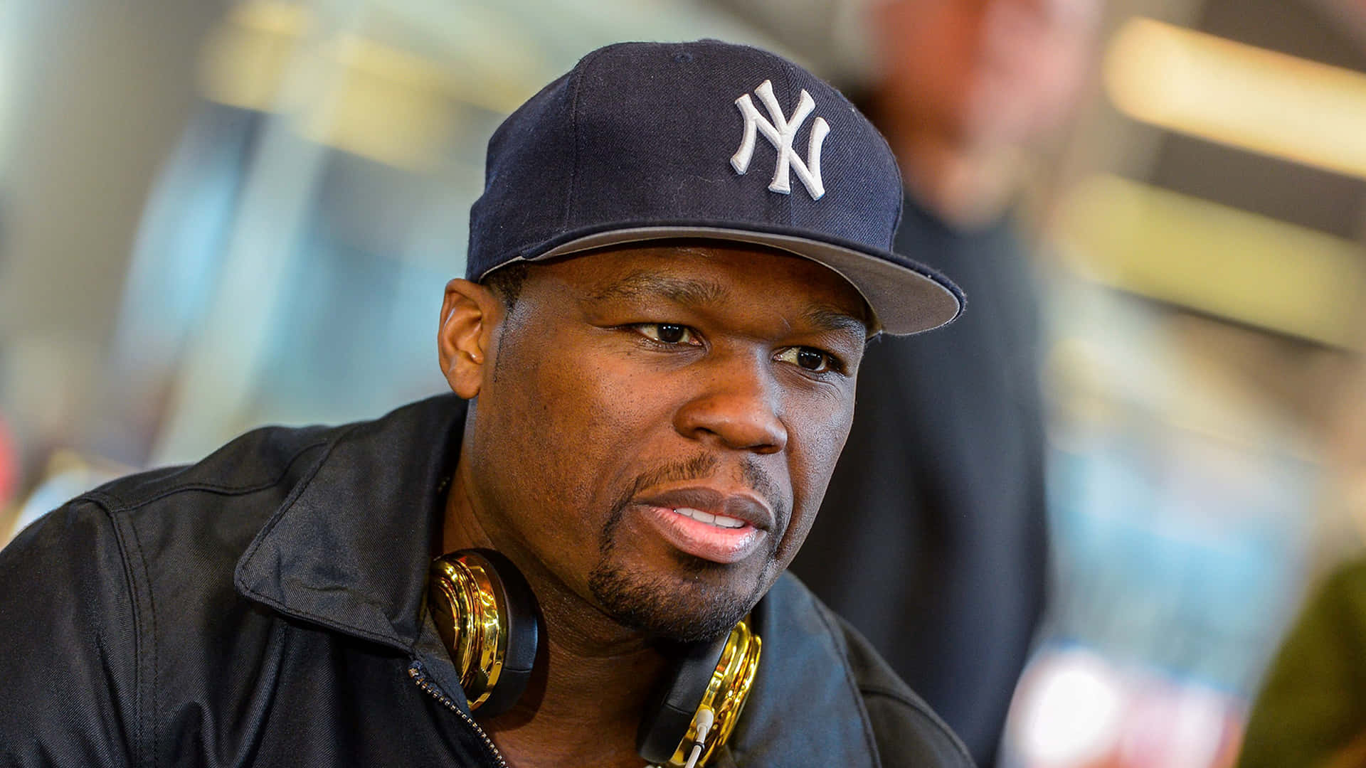 50 Cent 戴著洋基隊帽子和金色耳機的近距離肖像。