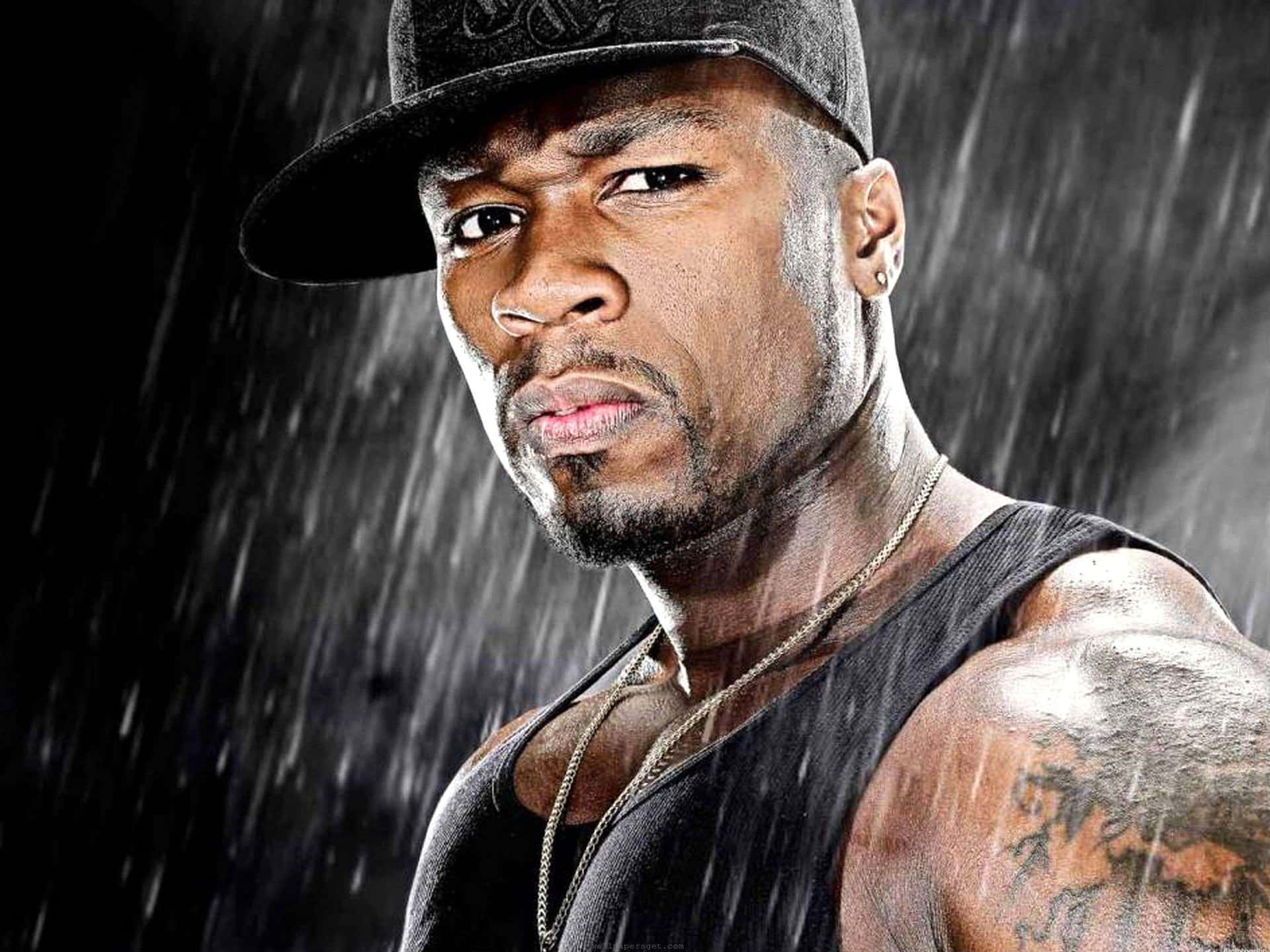 一個有紋身手臂和戴黑色帽子的男人在雨中凝視著。