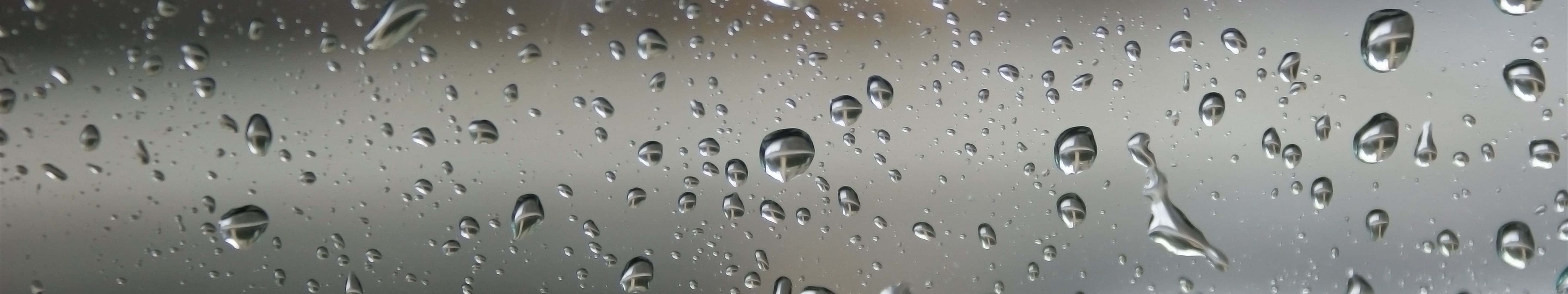 玻璃上的雨滴反射灰色天空