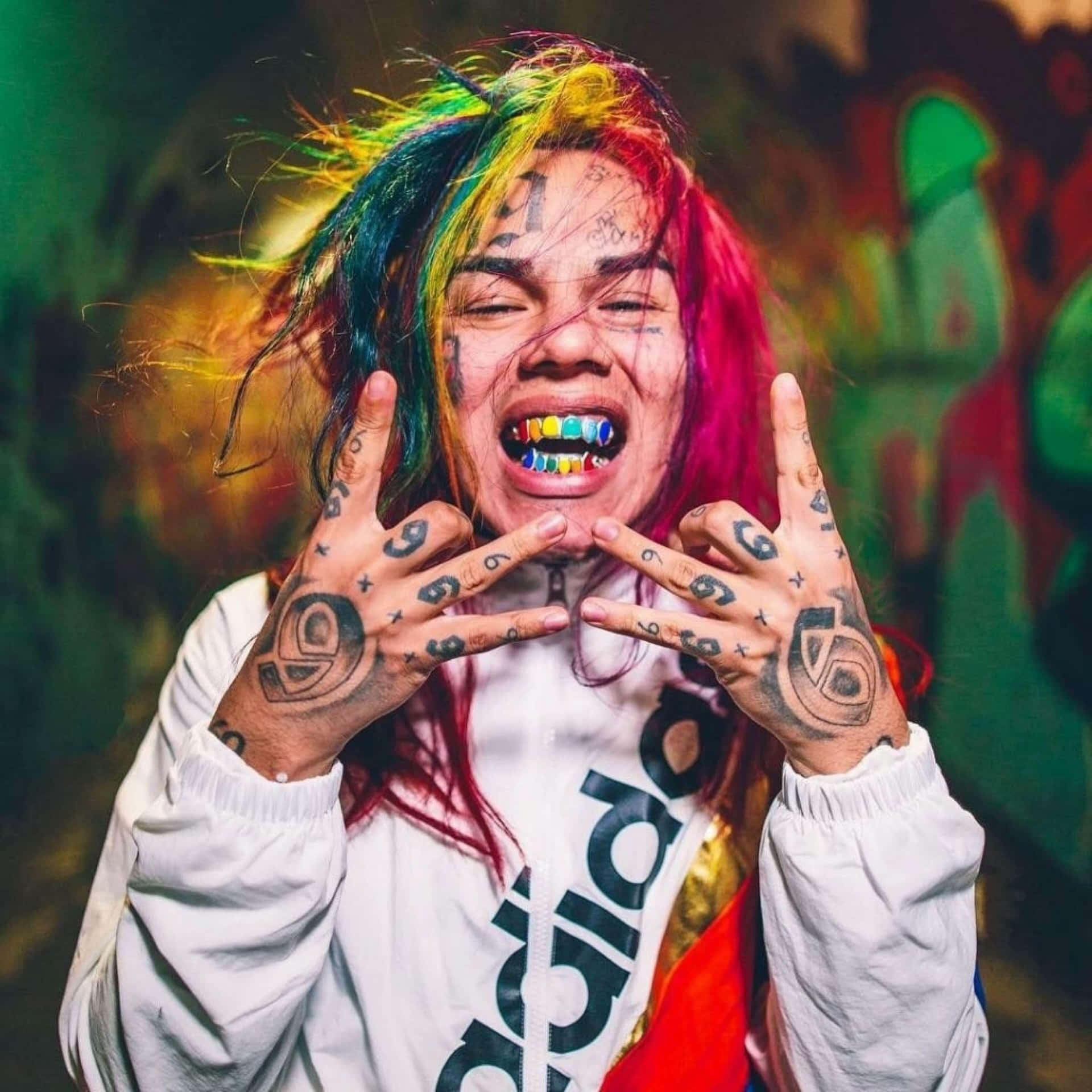 擁有彩虹頭髮和紋身的人做出搖滾手勢。