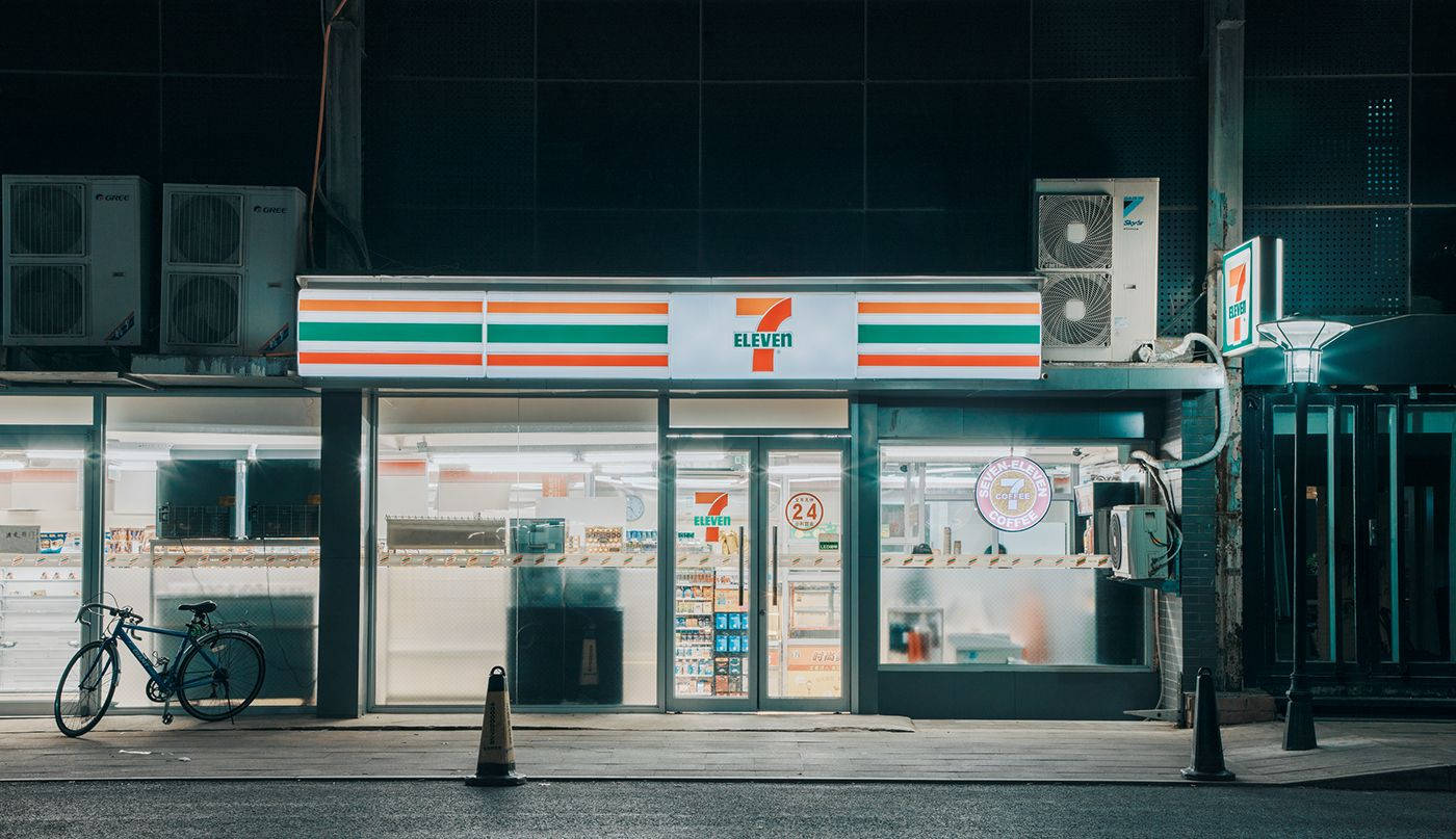 夜晚燈光明亮的7-Eleven商店，外面停著一輛單車。