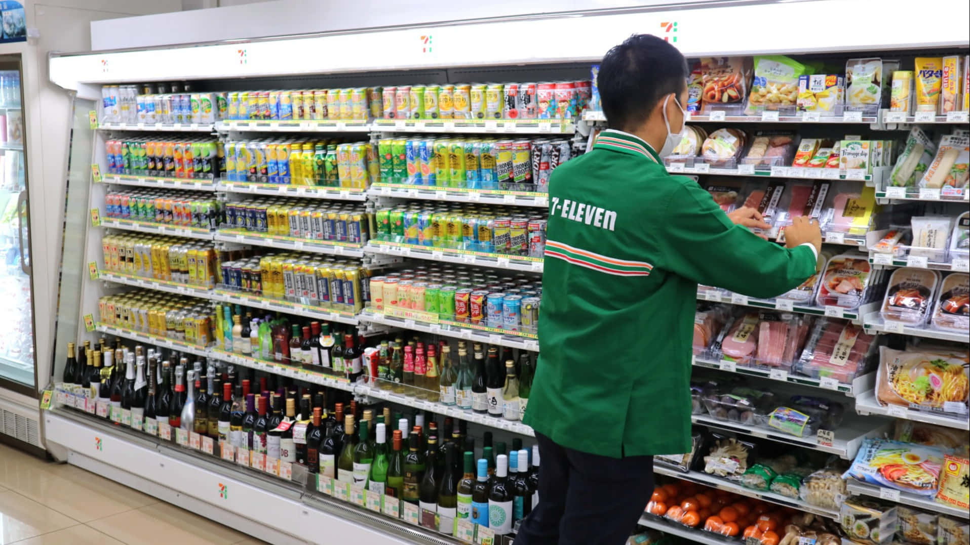 7-eleven員工在店內貨架上補充冷藏飲品和食品。