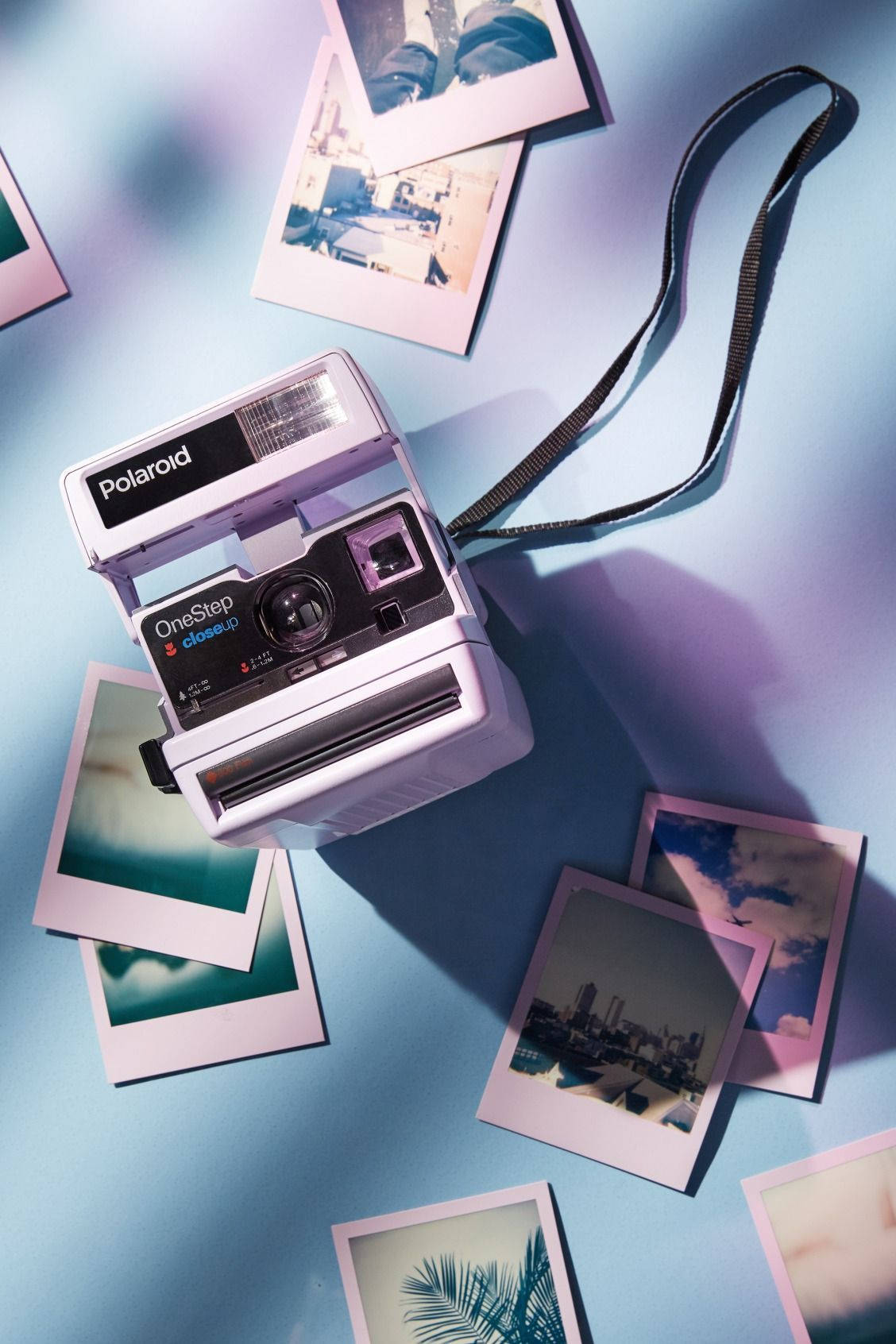 一部Polaroid相機被即影即有照片包圍在藍色表面上。 — 寶麗來 GIF 壁紙