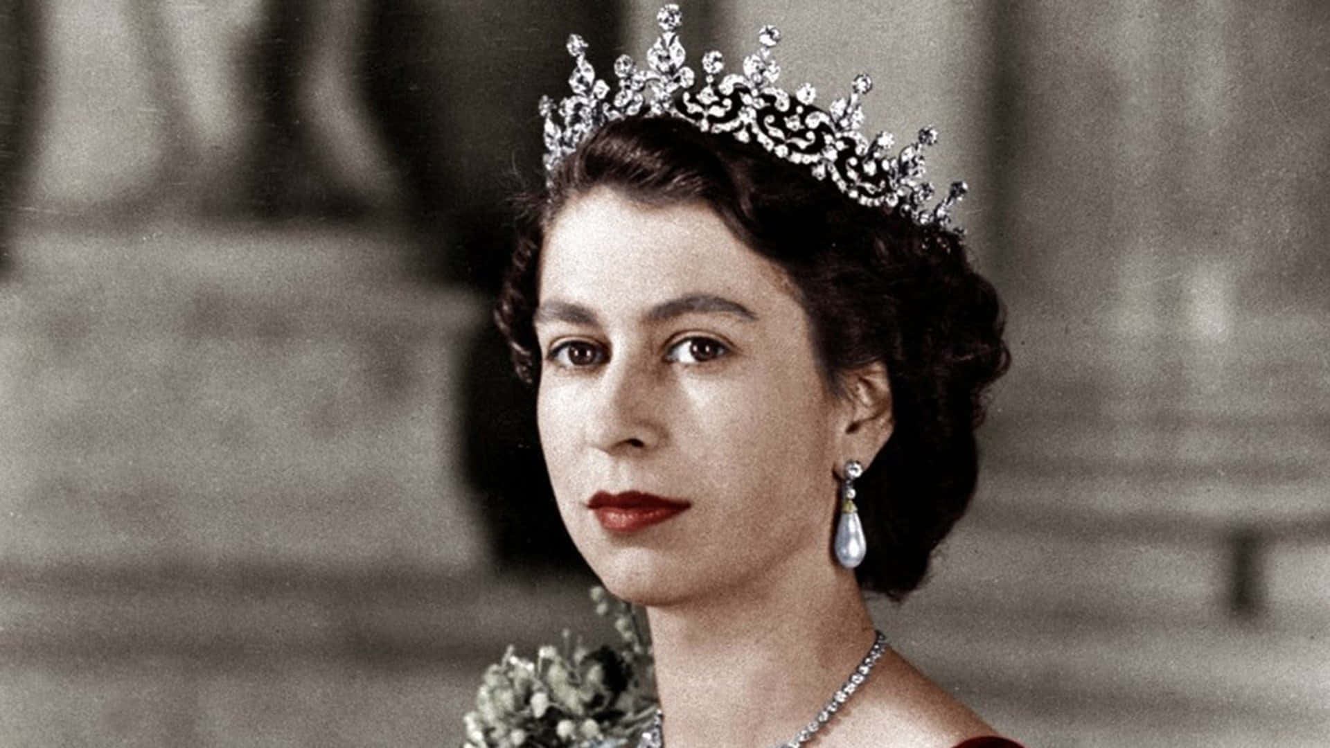 70年代的傳奇樂隊 - Queen 壁紙 — 一幅伊利沙伯二世女王的尊貴肖像，她佩戴閃爍鑽石皇冠、珍珠耳環和紅色唇膏，背景為柔和建築。