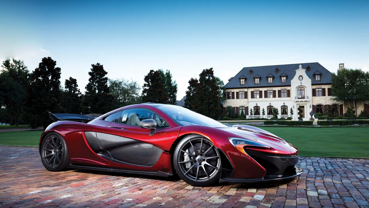 720p 麥拉倫720S的前衛設計 壁紙 — 一架亮麗的紅色McLaren P1超級跑車停泊在磚砌車道上，前方是一座宏偉的歐式豪宅，擁有修剪整齊的草坪和高大的樹木，背景是清澈的藍天。