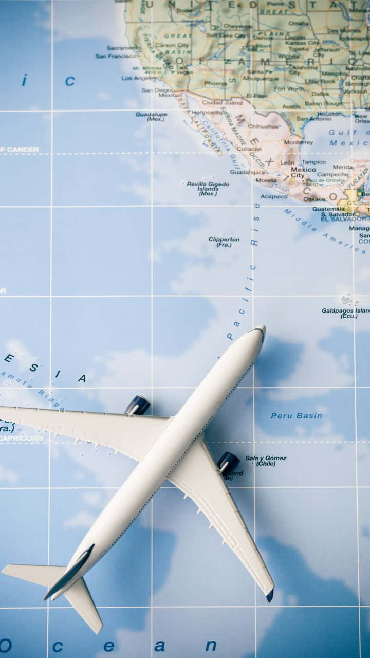 720p旅行背景：白色飛機模型置於地圖上 壁紙 — 一架白色飛機模型放在一張突出顯示太平洋和北美洲的世界地圖上。