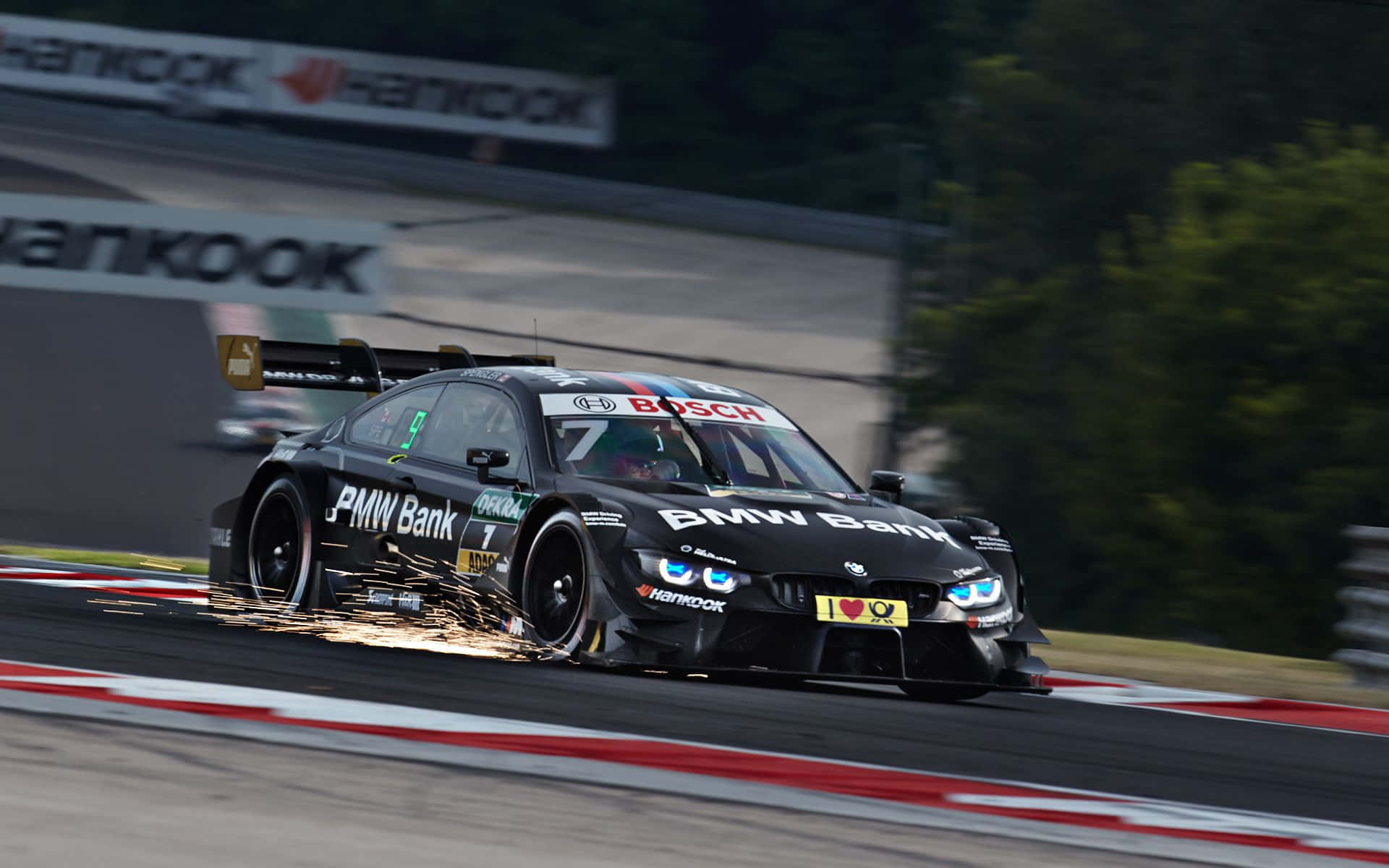 720p M系列背景：黑色賽車BMW M4 DTM 壁紙 — 一輛黑色寶馬賽車帶有發光的藍色頭燈，在高速過彎時與賽道擦出火花。