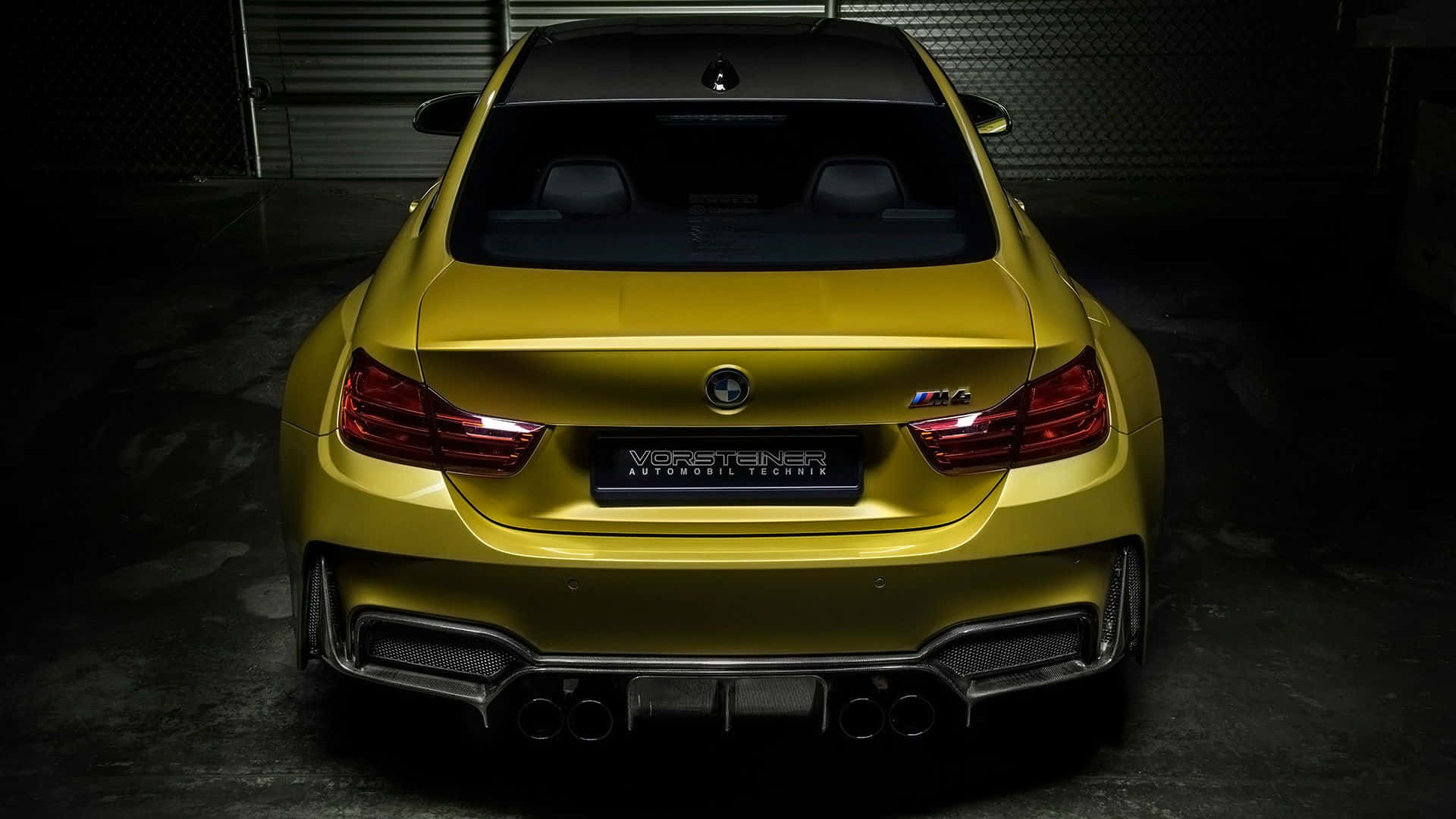 光澤黃色改裝BMW M4跑車在黑暗車庫中的後視圖。