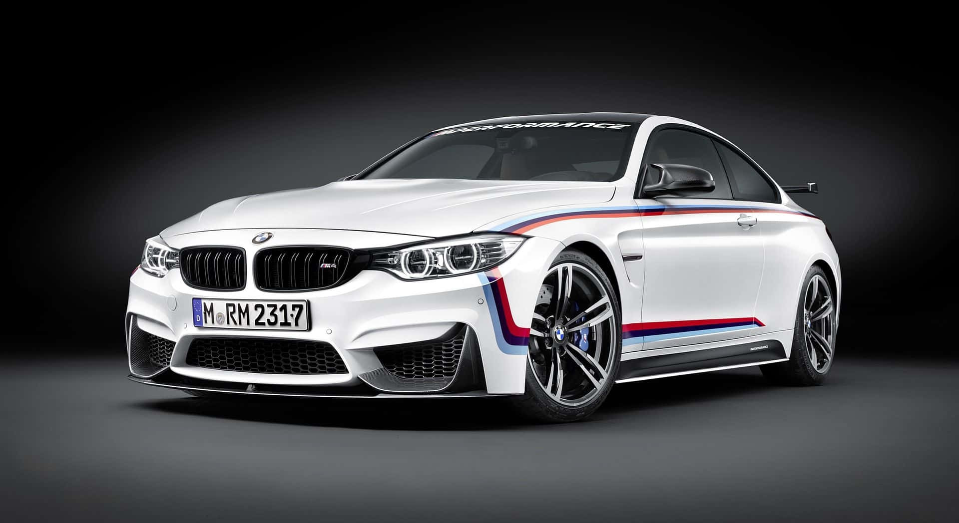 白色BMW M4雙門轎跑車，帶有賽車條紋，在工作室燈光下。