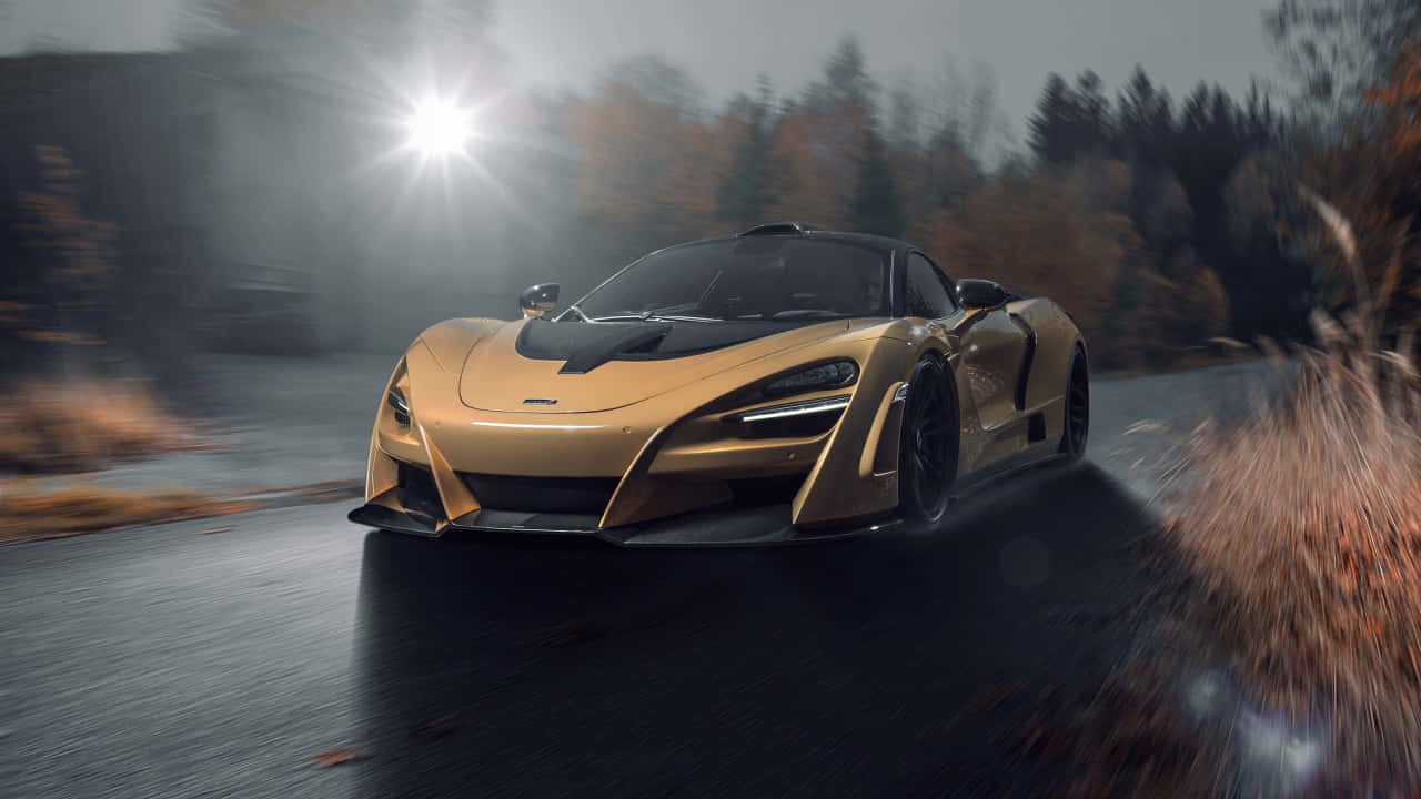 720P 麥拉倫720S 淡雅背景 壁紙 — 一輛金色McLaren跑車在明亮的陽光照射下，沿著潮濕的森林道路疾馳，秋天的樹木呈現動態模糊效果。