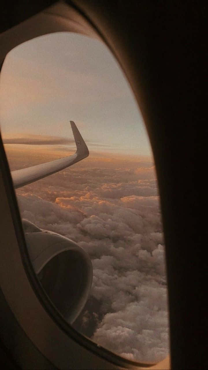 720p旅行背景 - 飛機窗邊的雲景 壁紙 — 透過飛機窗戶看到金色日落雲層上的飛機機翼和引擎。