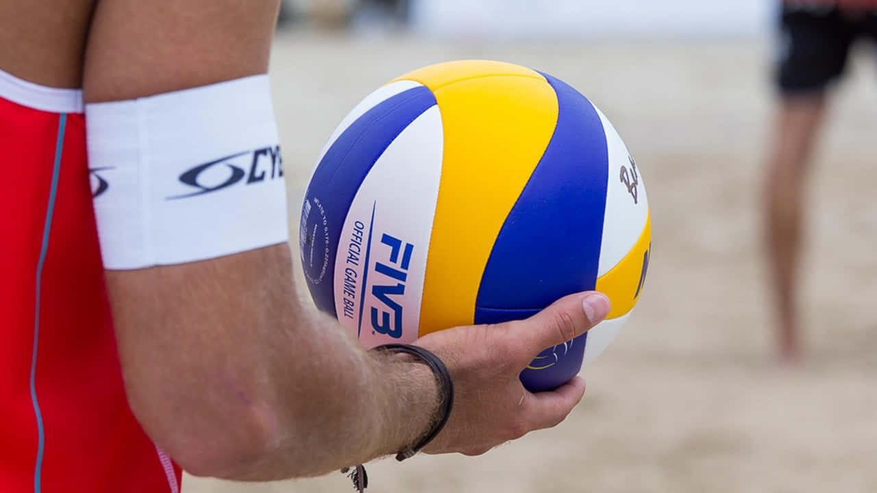 運動員在沙上手持官方FIVB沙灘排球。