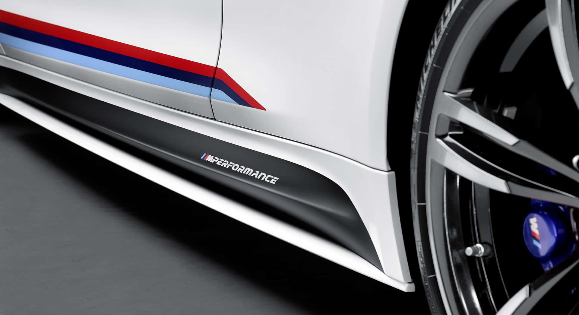 白色BMW M Performance汽車側面板，帶有藍、紅、白條紋和合金輪圈。