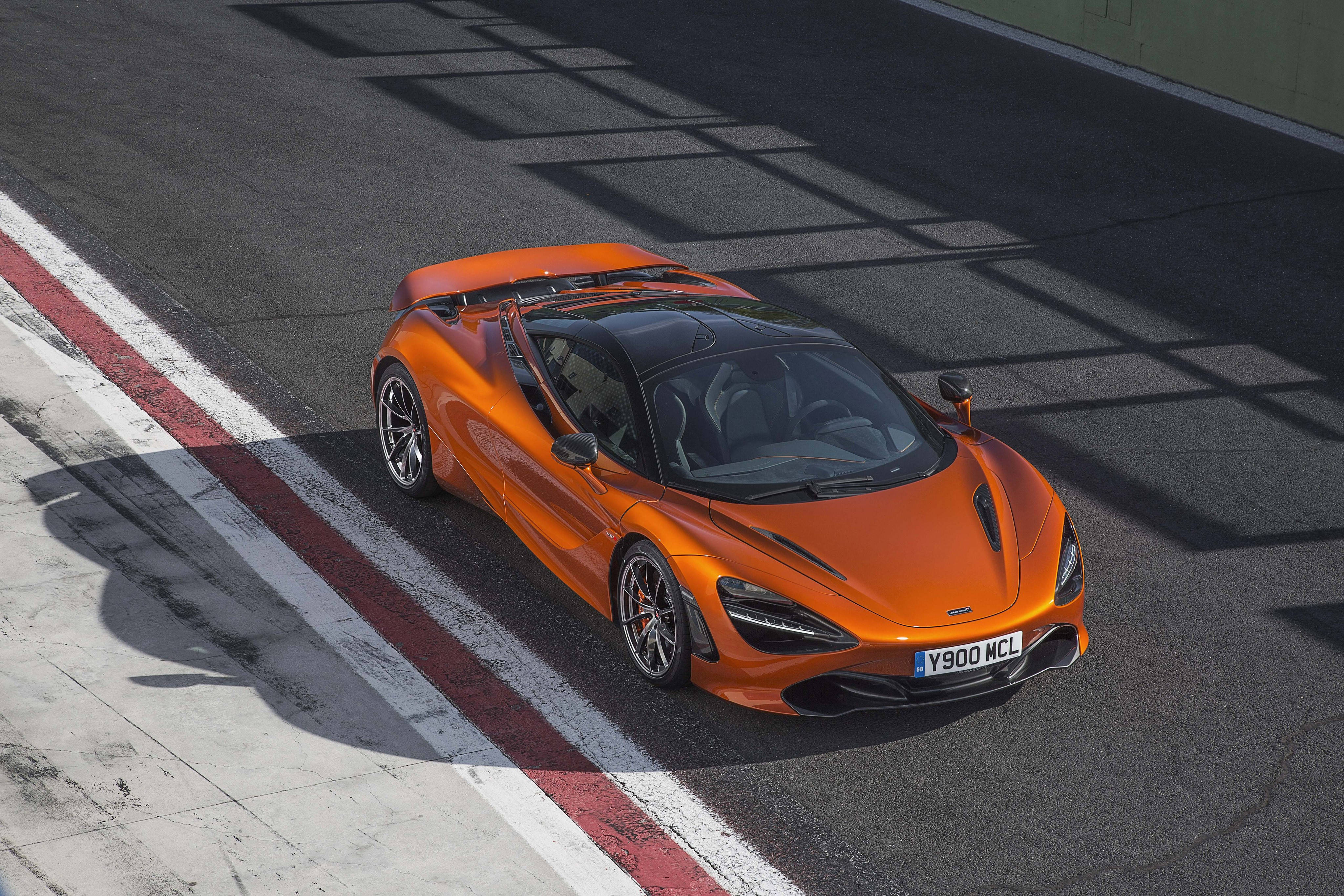 麥拉倫720s 4K行駛於道路 壁紙 — 一輛充滿活力的橙色McLaren 720S跑車在陽光照耀的賽道上奔馳，上方結構投下清晰的陰影。