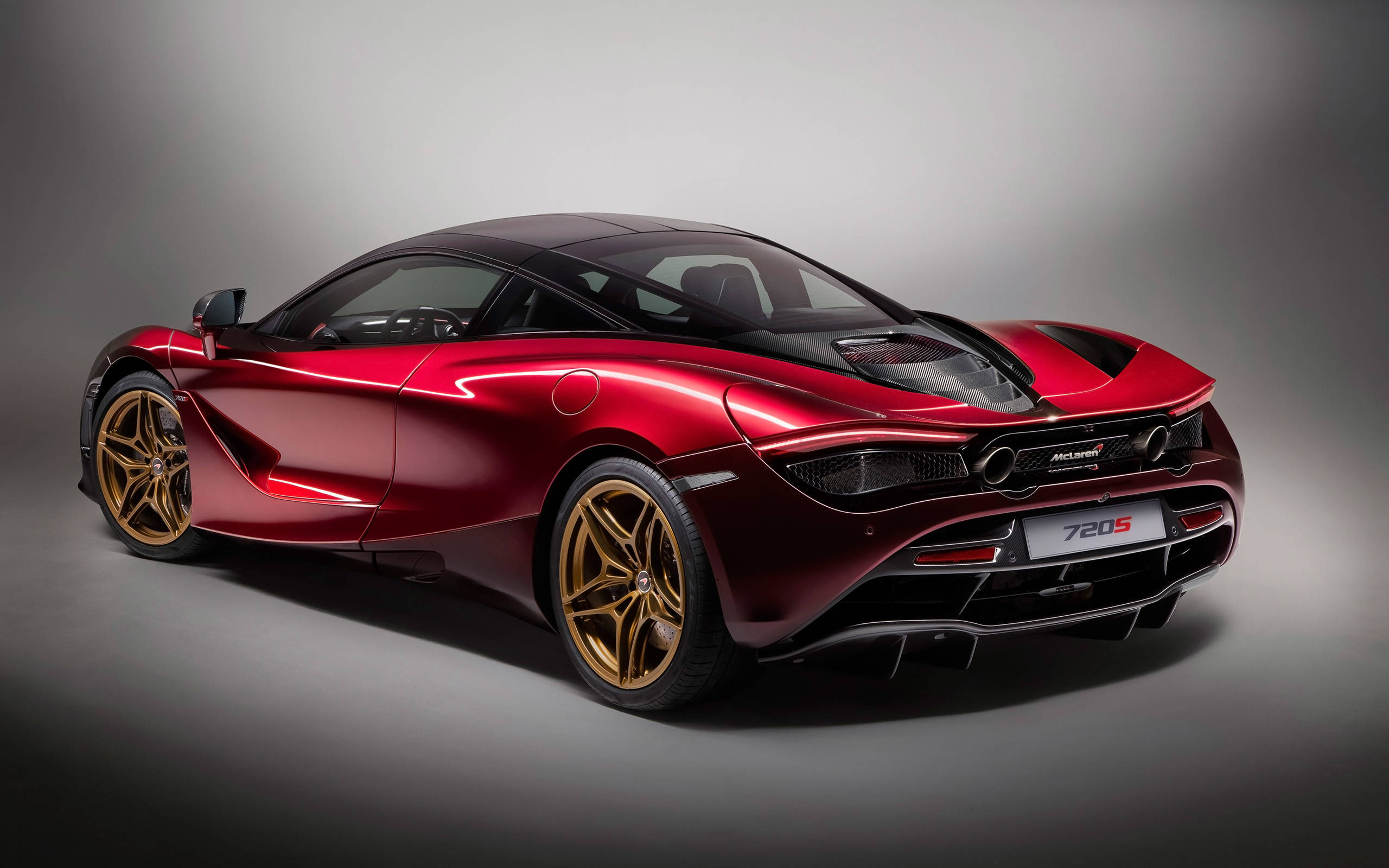 紅色麥拉倫720s 4K 壁紙 — 一輛光澤的紅色McLaren 720S跑車配金色輪圈，在戲劇性照明的攝影棚中展示。