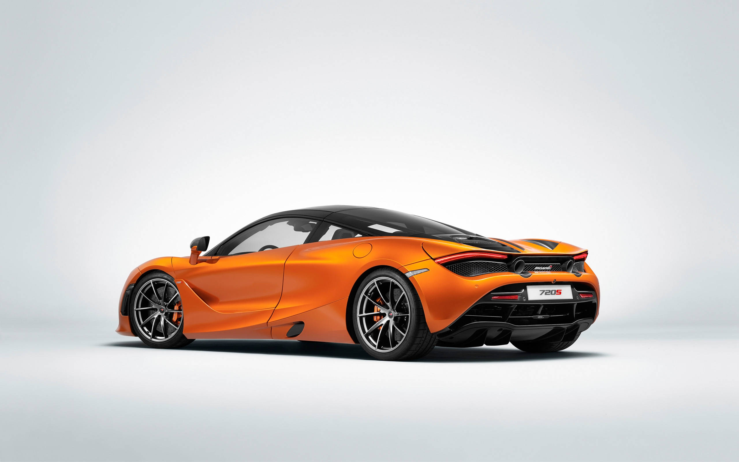 新款麥拉倫720S 4K 壁紙 — 一輛充滿活力的橙色McLaren 720S跑車在簡約的攝影棚環境中展示，背景為純白色。
