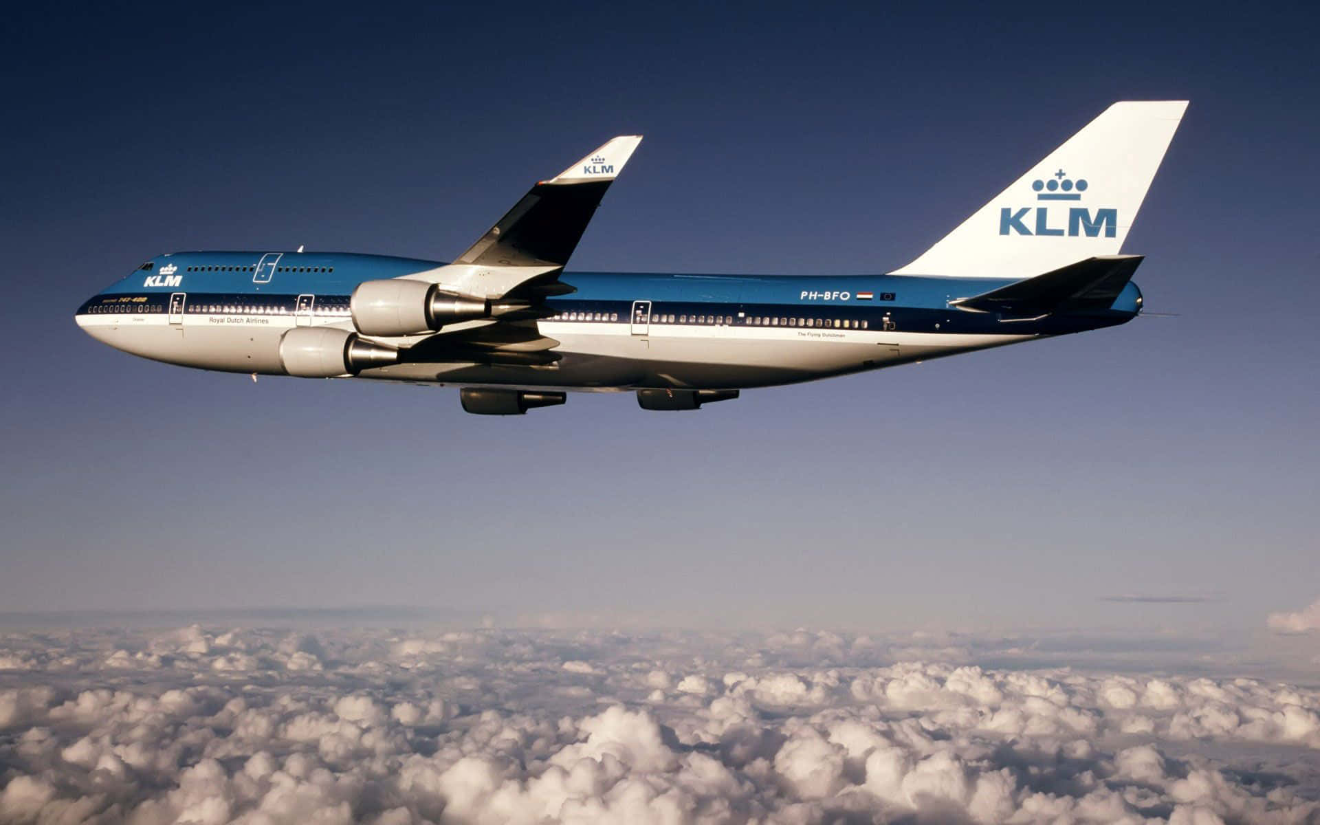 波音747飛越天際 壁紙 — 一架KLM波音747在晴朗藍天下，優雅地翱翔於大片蓬鬆白雲之上。