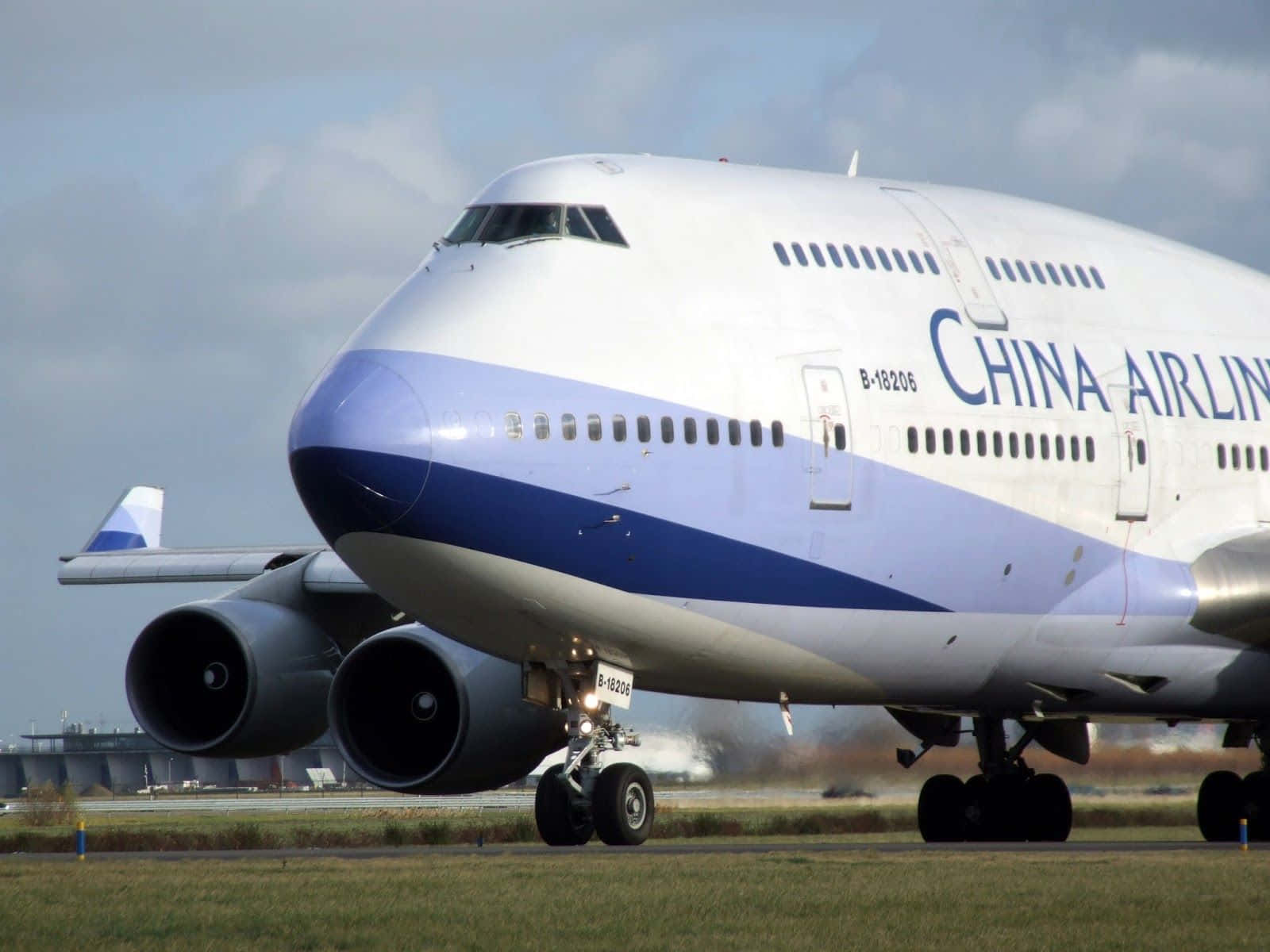波音747飛機的空中拍攝 壁紙 — 一架中華航空波音747在跑道上滑行，背景是草地和陰天。