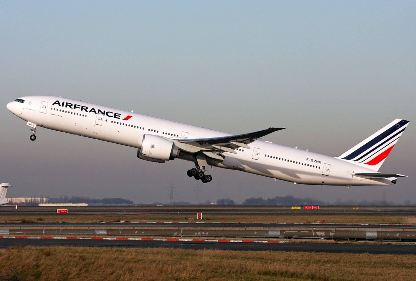 法國航空波音777-200 F-GSPT客機起飛 壁紙 — 一架法國航空波音777從跑道起飛，起落架伸出，背景是朦朧的天空。