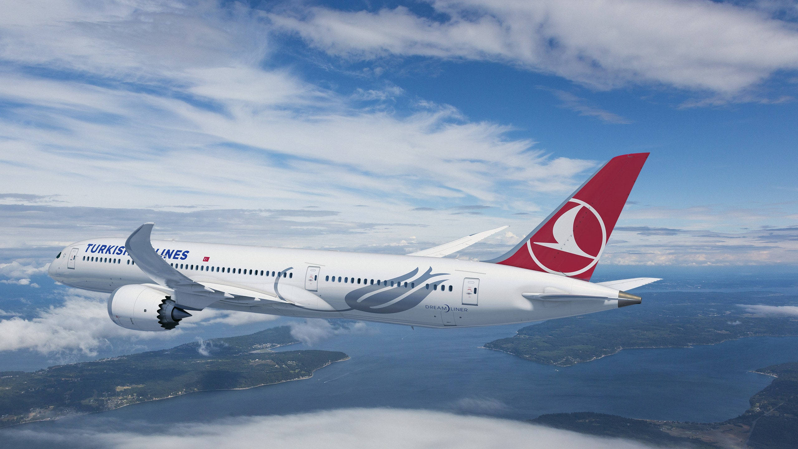 土耳其航空波音787-9夢想飛機 壁紙 — 土耳其航空波音 787 夢想客機在明亮的藍天和散落的雲朵下翱翔於沿海島嶼之上。