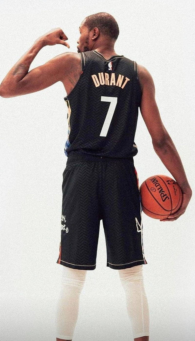 7號 Kevin Durant 酷炫手機壁紙 壁紙 — 運動員凱文·杜蘭特穿著黑色7號球衣，拿著籃球，展示他的二頭肌。
