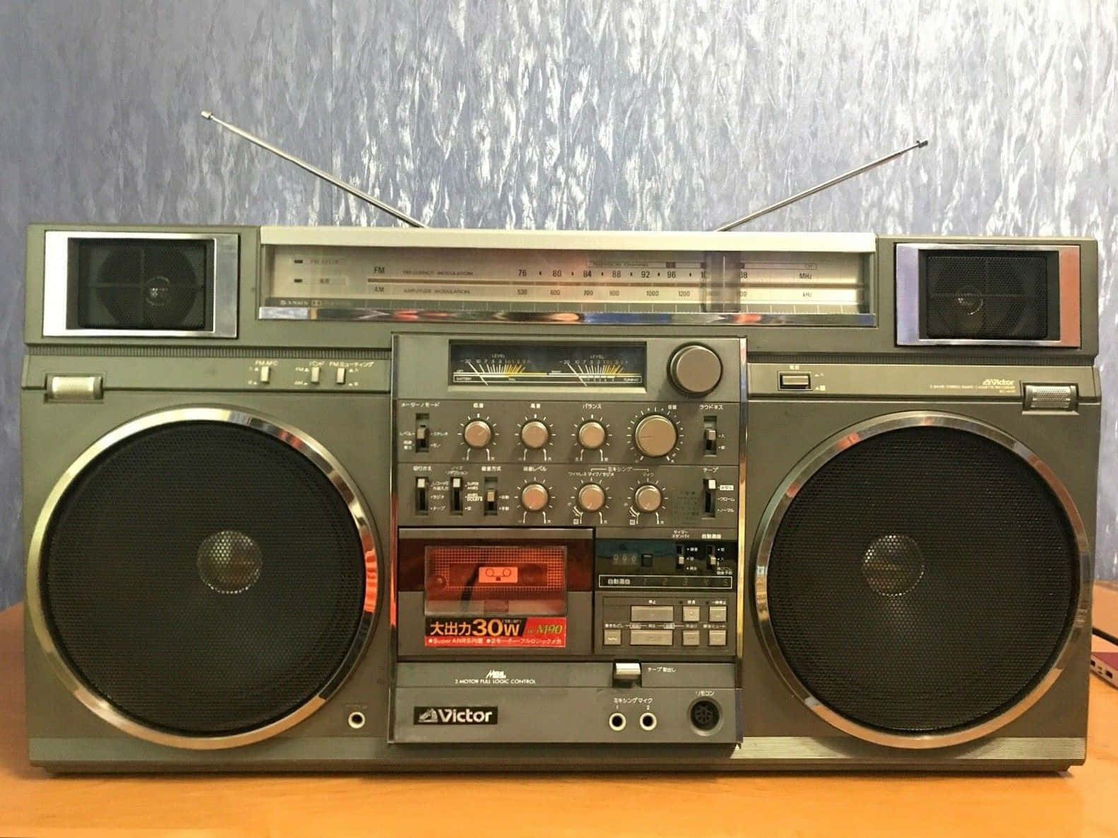 橄欖綠色復古手提音響，帶有鍍鉻細節和伸長的天線，放在木桌上。