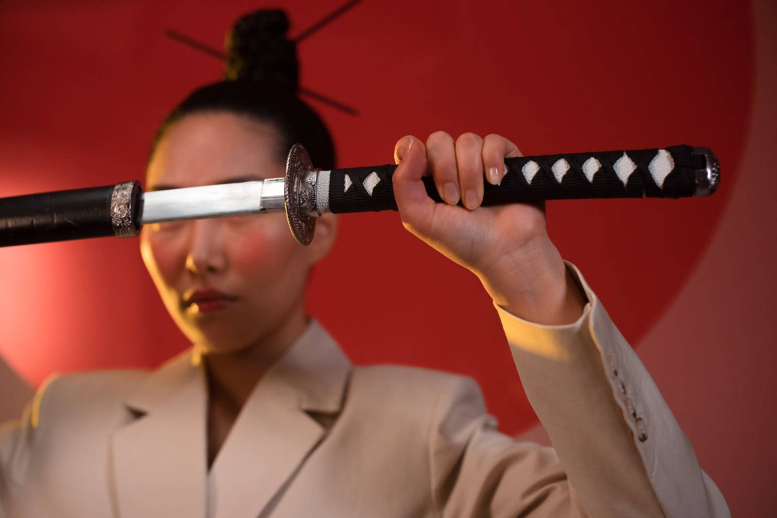 8K武士穿米色西裝 壁紙 — 一名身穿米色西裝的人將武士刀水平橫在臉前，背景為鮮紅色。