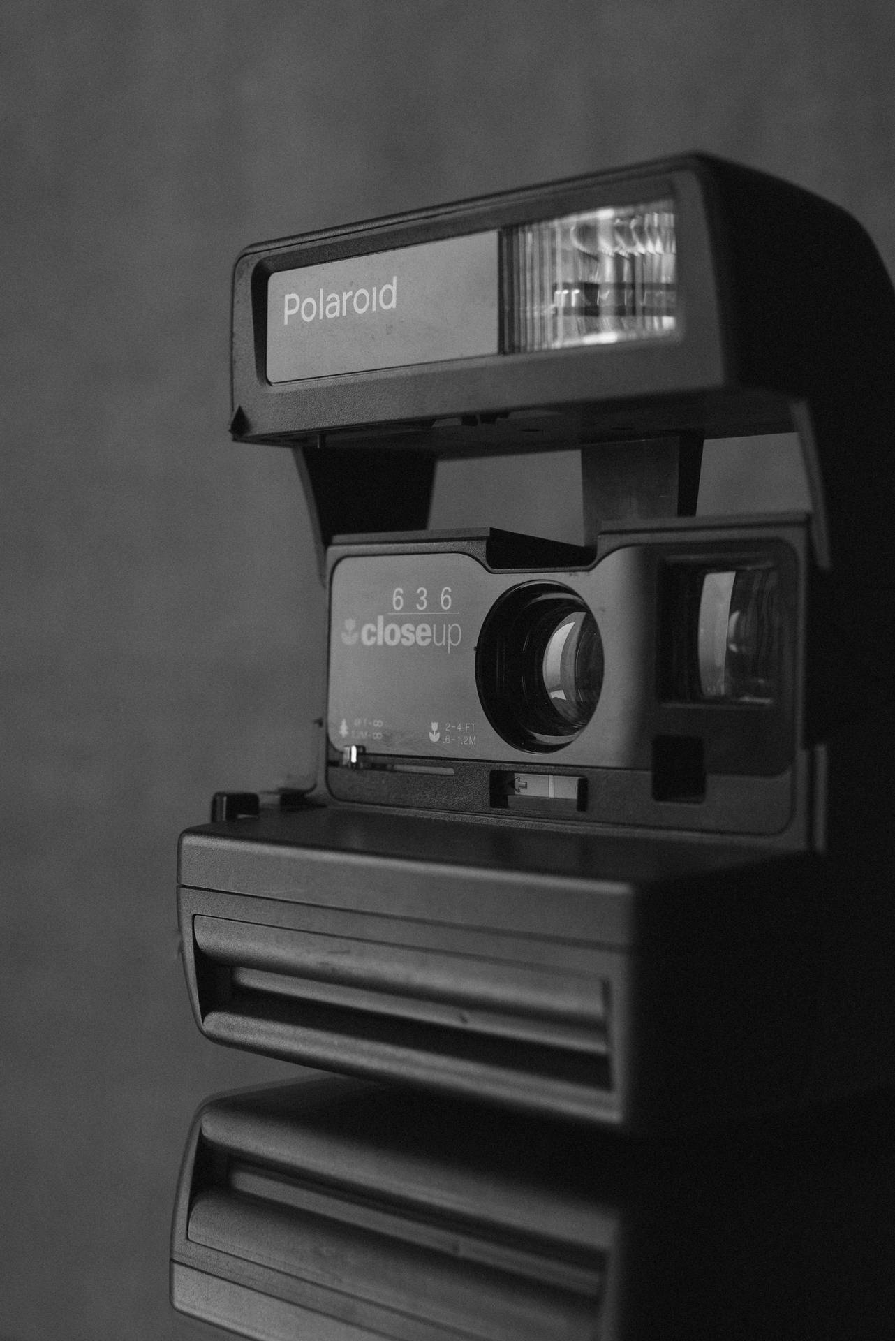 復古Polaroid 636近攝相機，閃光燈亮起，反射在深色表面上。