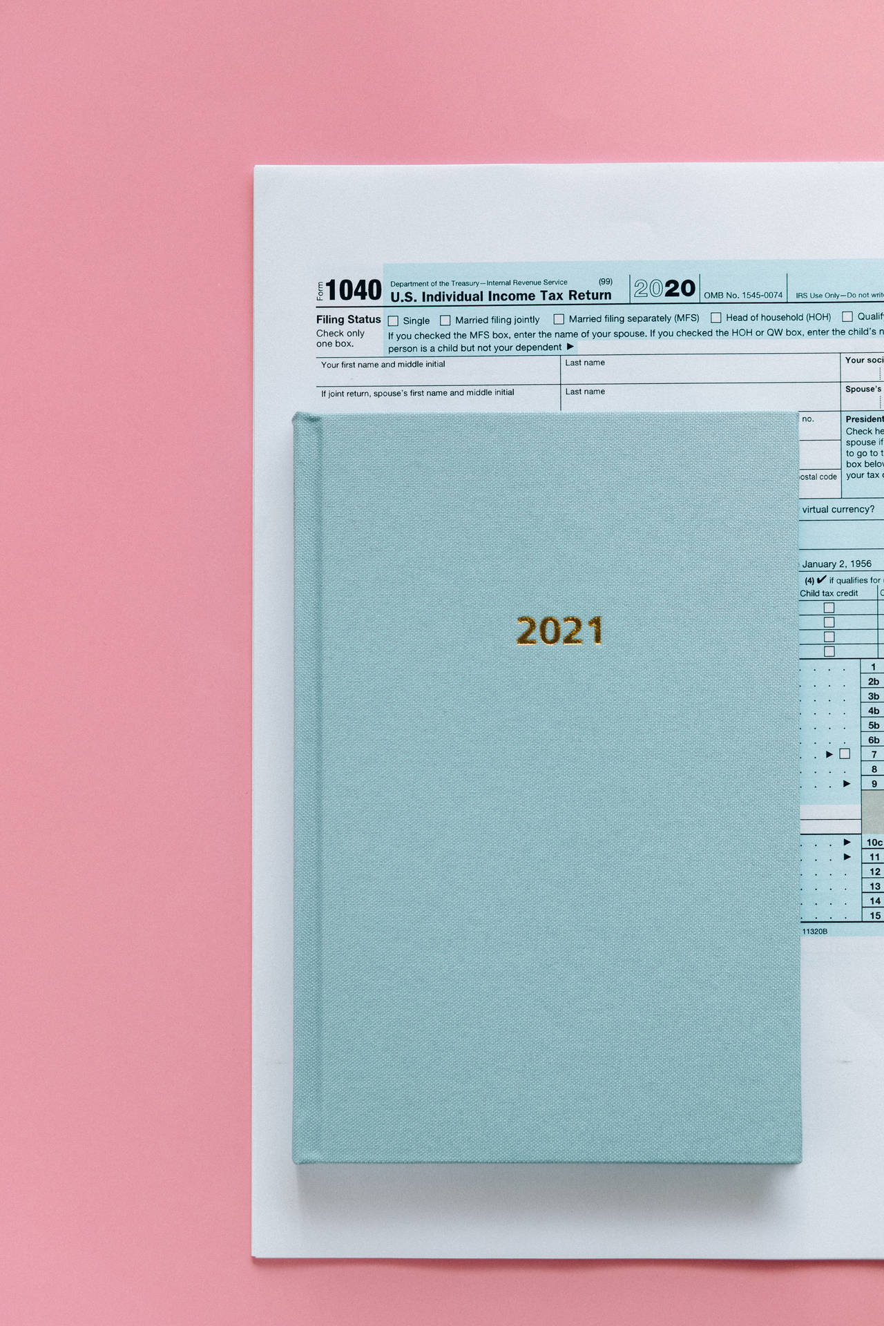 藍色文件夾標有2021，放在2020年稅表上，背景為粉紅色。