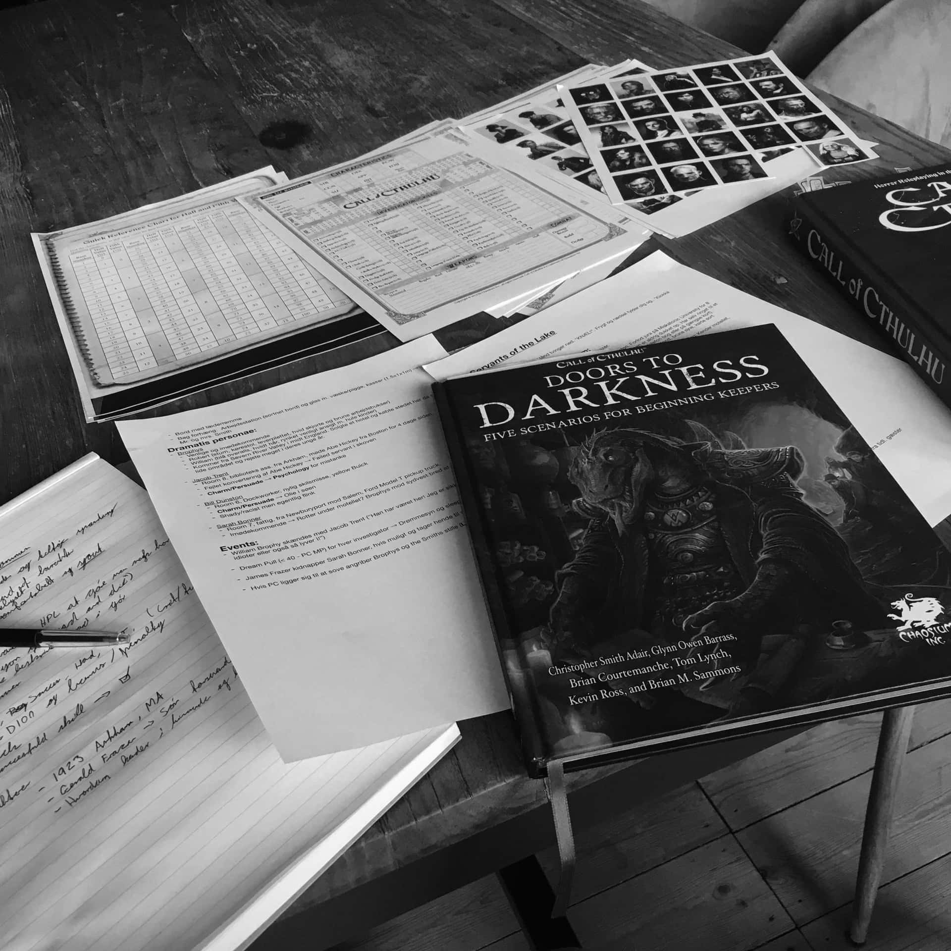  壁紙 — 一個黑白桌面場景，展示 Call of Cthulhu 遊戲設置，包括規則書、角色表和手寫筆記。