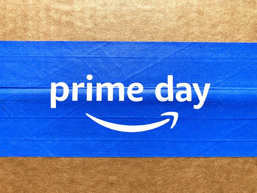  壁紙 — 一個藍色Amazon Prime Day橫幅，帶有白色文字和微笑標誌，貼在棕色紙板上。